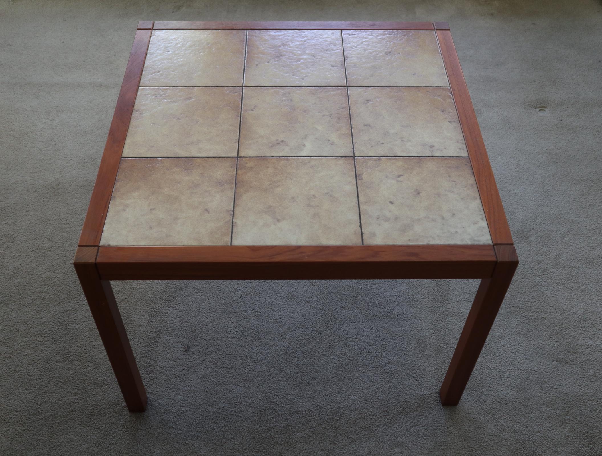 Lovely elegant coffee table. Square teak frame and legs with neutral tiles. Teak even in color and tile has no breaks or damage. Normal wear. Legs unscrew for safe transport. Stamped Denmark to underside of table. Perfect for use as coffee or