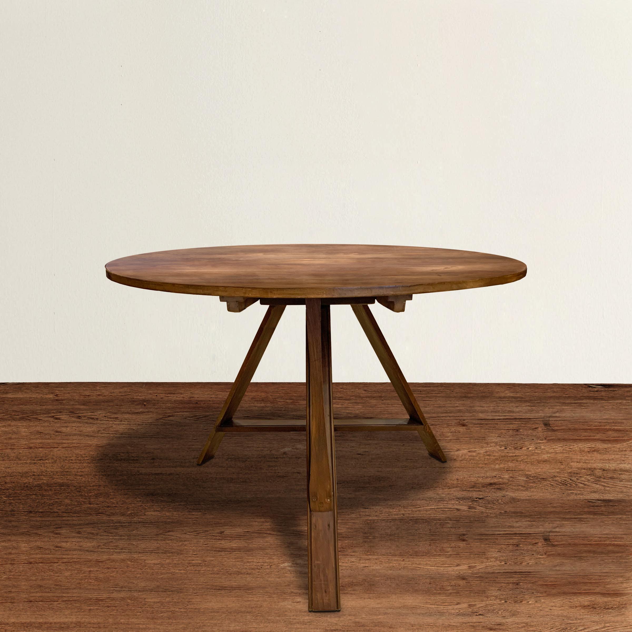 A beautiful Danish Mid-Century Modern round tilt-top table constructed from pine, and with three legs with carved beaded edges and trestle-style stretchers. Table is perfect for dining, a breakfast nook, or used as a side table next to a sofa or a
