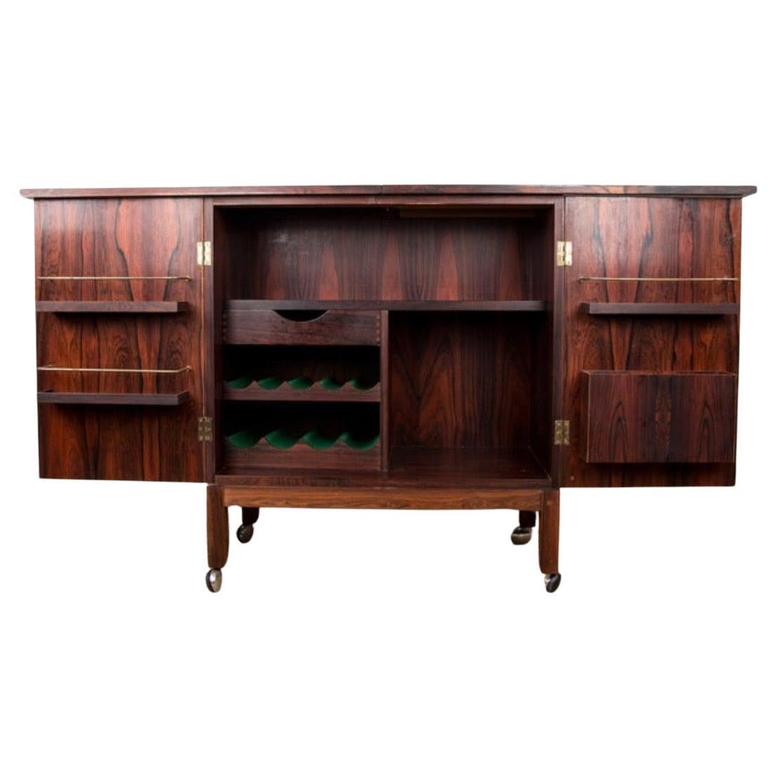 Desirable rosewood bar cabinet designed by Torbjørn Afdal for Bruksbo of Norway. Locking cabinet opens to reveal storage for all necessary bar accoutrements. Black laminate flip-top doubles in size for additional working space. Bar is complete with
