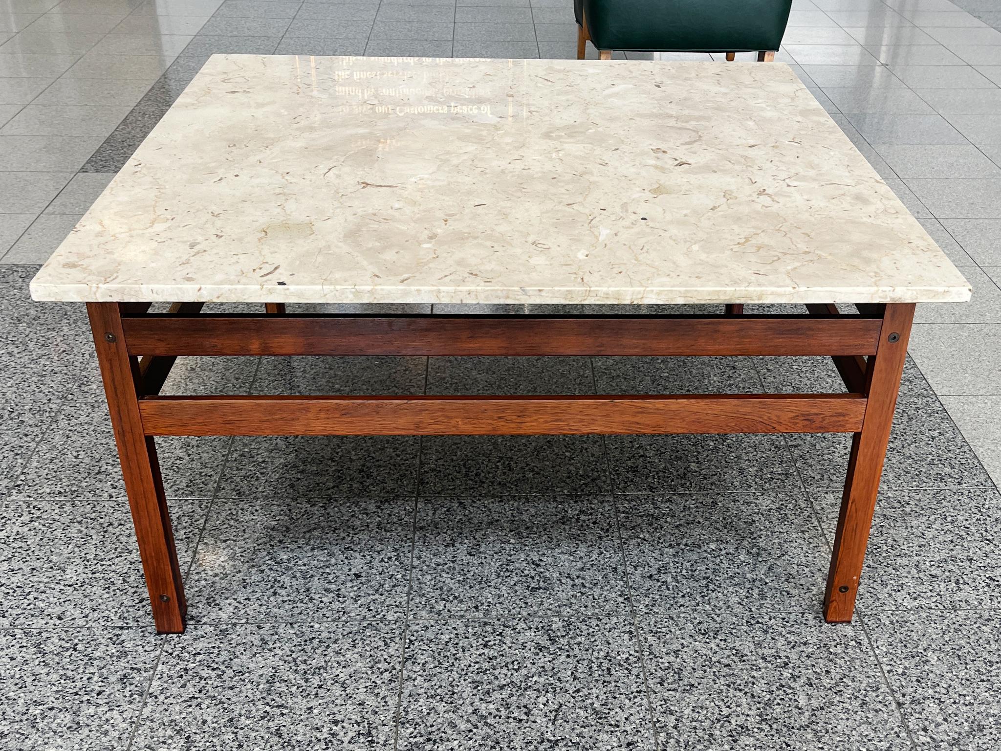 This classic Mid-20th Century square coffee table consists of a travertine top and a rosewood base. The design is characterized by clean lines, simple shapes, and symmetry. A good height and open structure to the base gives the overall architecture