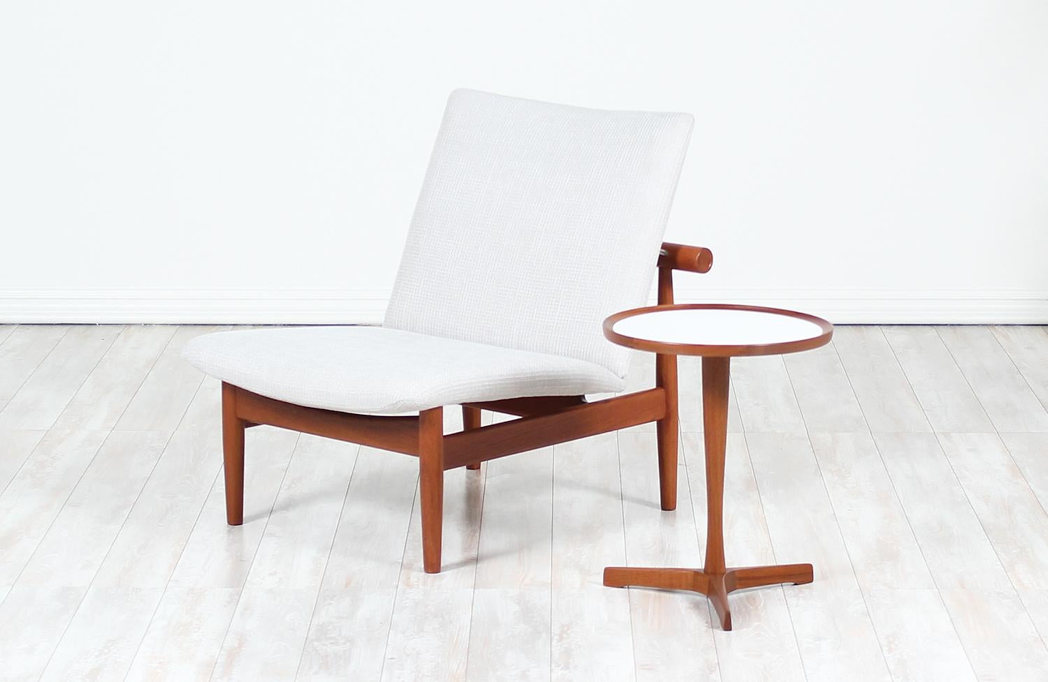 Elegant tri-leg side table designed and manufactured by Hans C. Andersen in Denmark circa 1950s. This minimalist side table features a sculpted base comprised of three legs and its original white laminate inlaid round top. This table has been