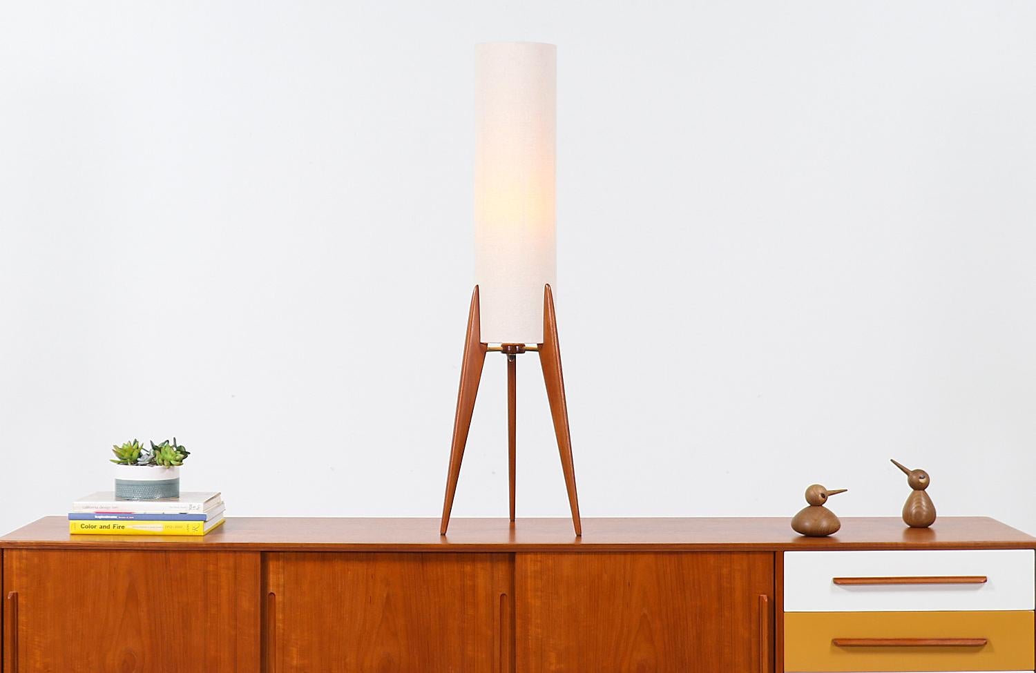 Elegant tripod table lamp designed and manufactured in Denmark, circa 1960s. This rare Danish modern design features a tripod teak base that holds the new custom cylindric linen shade adding a warm flair of light to any room. The three teak legs