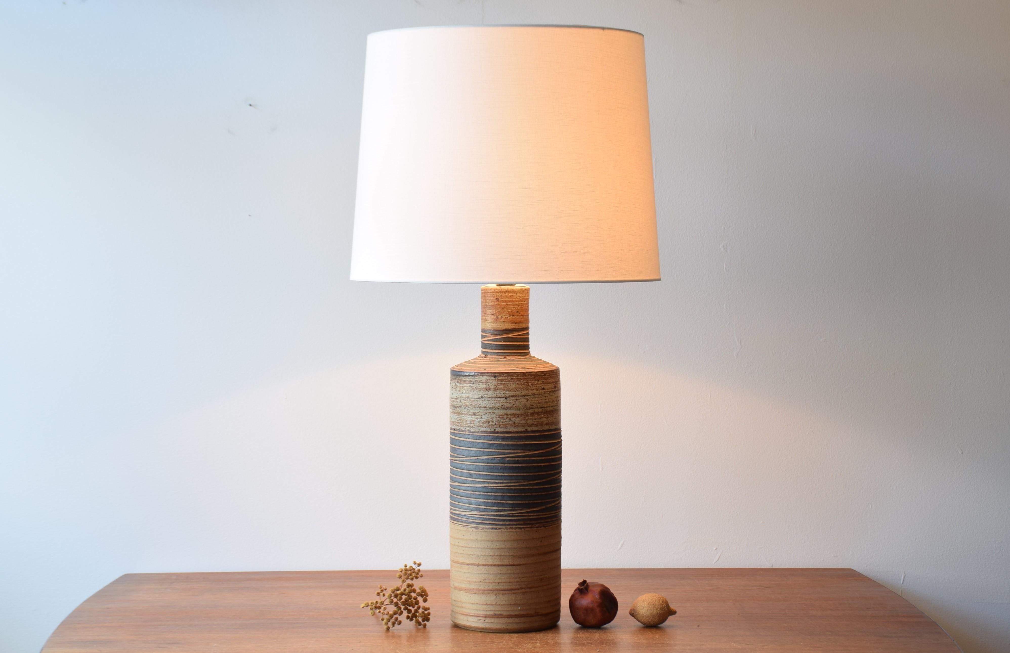 Very tall table lamp including lamp shade by Danish ceramist Tue Poulsen (born 1939). Made ca. 1970s in Tue Poulsen´s own studio.
The base is made of chamotte clay and is decorated with insised stripes and glaze in brown, beige and black and it´s