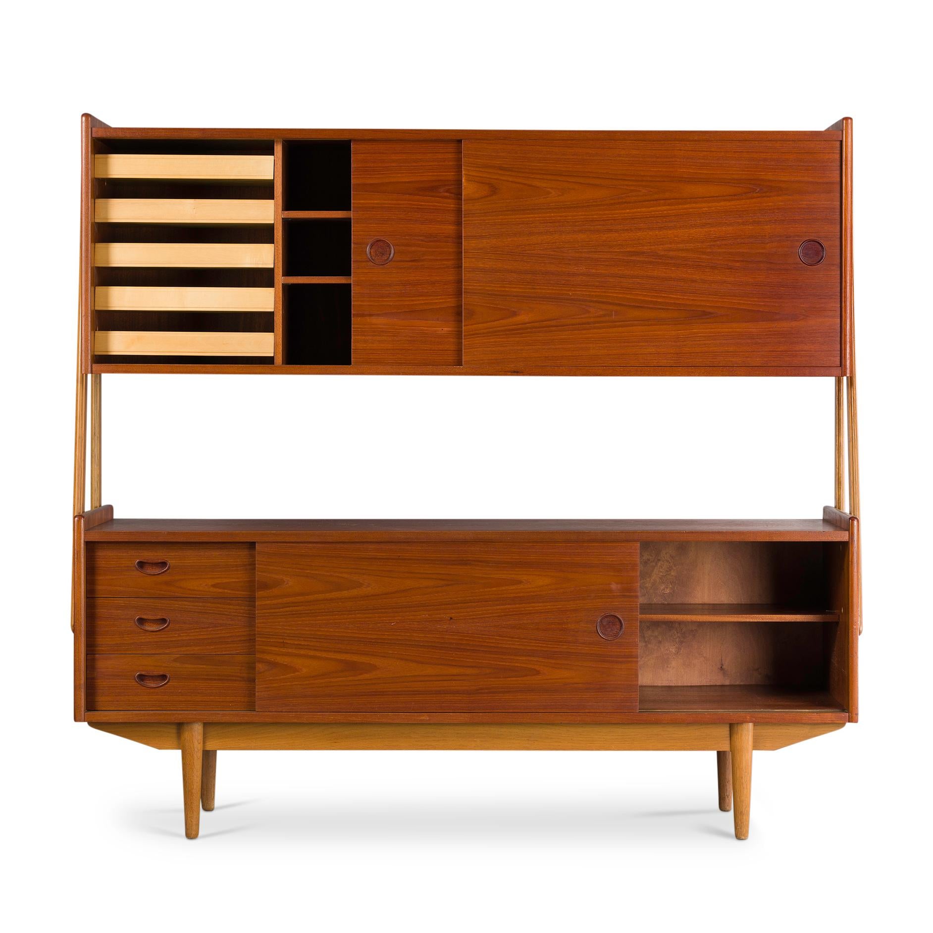 This Danish beauty is constructed out of solid oak and teak veneer. The hutch or upper segment of this two-tier chest or credenza is held up by two pairs of organically shaped solid oak legs. The teak veneer is placed on top of solid beach wood.