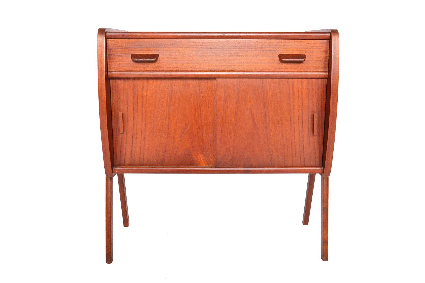 This gorgeous Danish modern midcentury V-legged entry chest will make a great addition to any modern room or entry way. Crafted in teak, the case provides a drawer and a spacious oak- lined interior accessible by sliding doors. Piece stands on solid