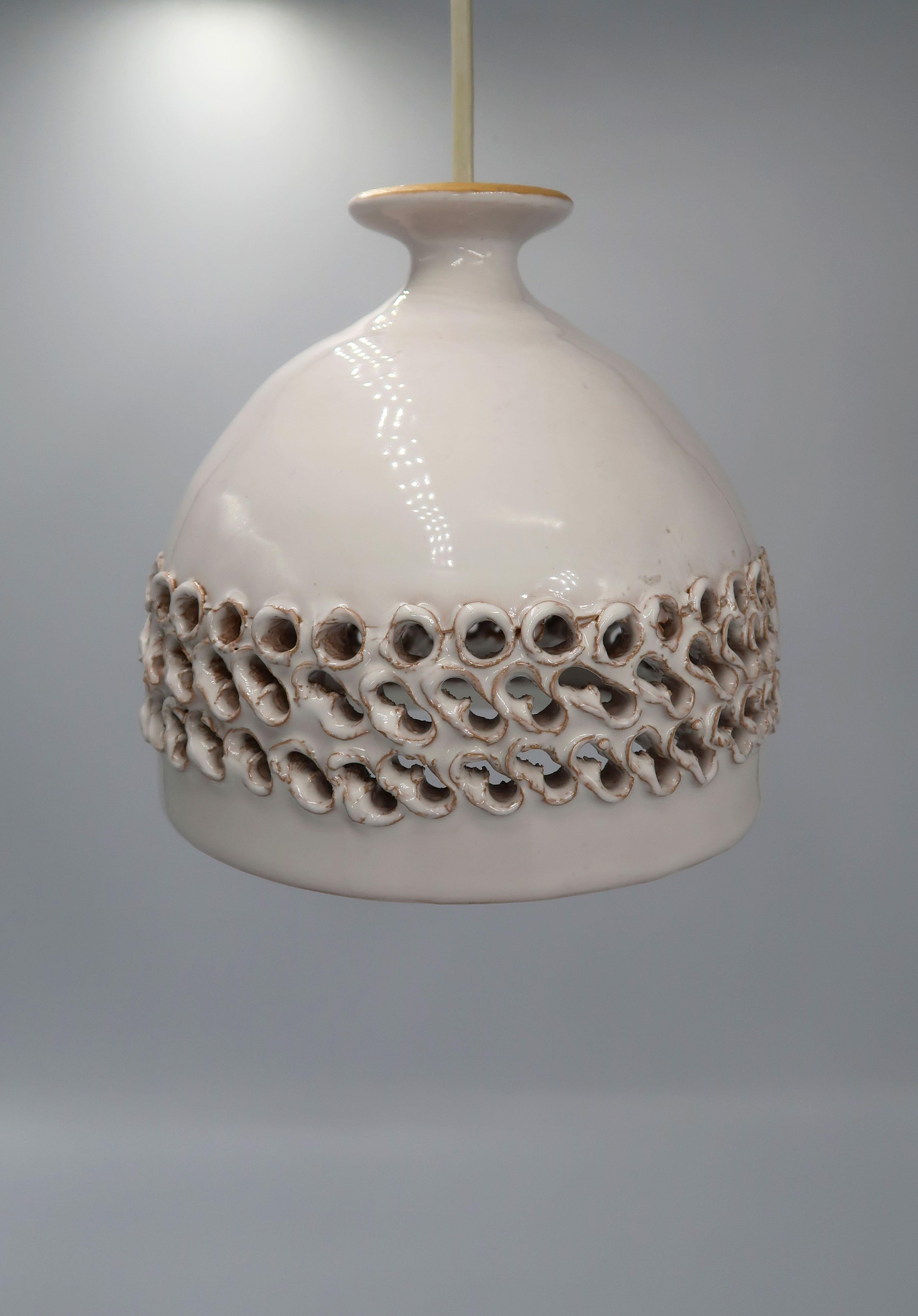 Beautiful Danish Mid-Century Modern handmade ceramic cream white glazed pendant. Three bands of handmade irregular perforated pattern around the belly of the pendant to let out light. Warm cream white shiny glazing on the exterior. Estimated