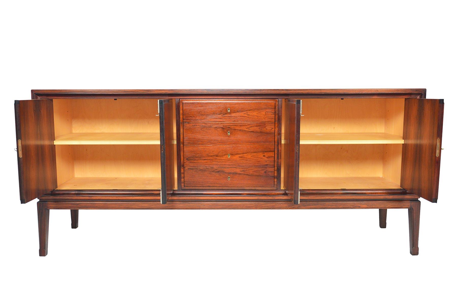 This stunning Danish modern rosewood credenza features traditional design details in a modern package! The flush face is free of handles or drawer pulls and uses original keys as pulls. Beautiful routed banding adorns the doors and drawers. Two