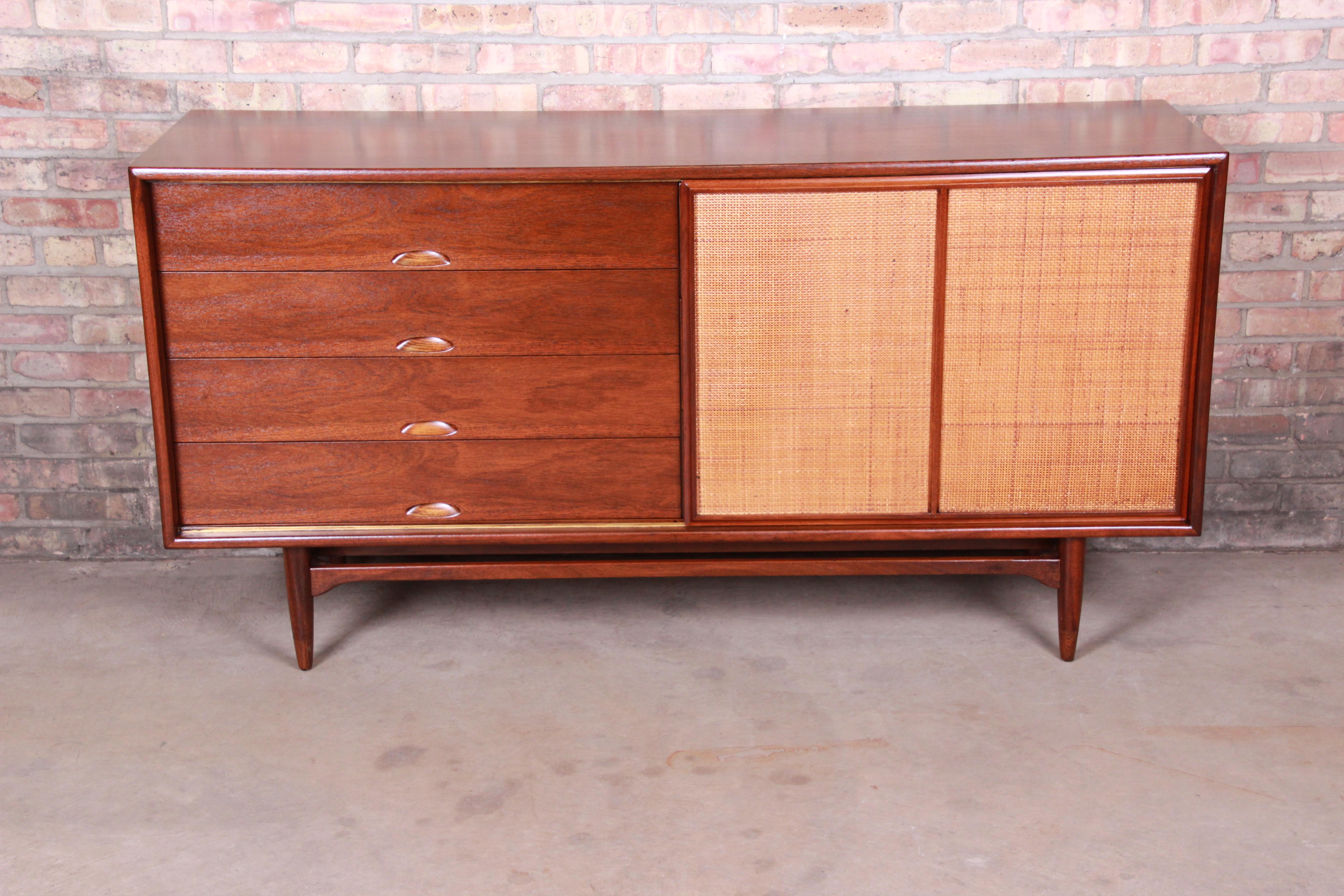 An exceptional midcentury Danish modern style 10-drawer dresser or credenza

In the manner of Finn Juhl for Baker Furniture

circa 1960s

Sculpted walnut, with recessed drawer pulls and sliding cane front door.

Measures: 66