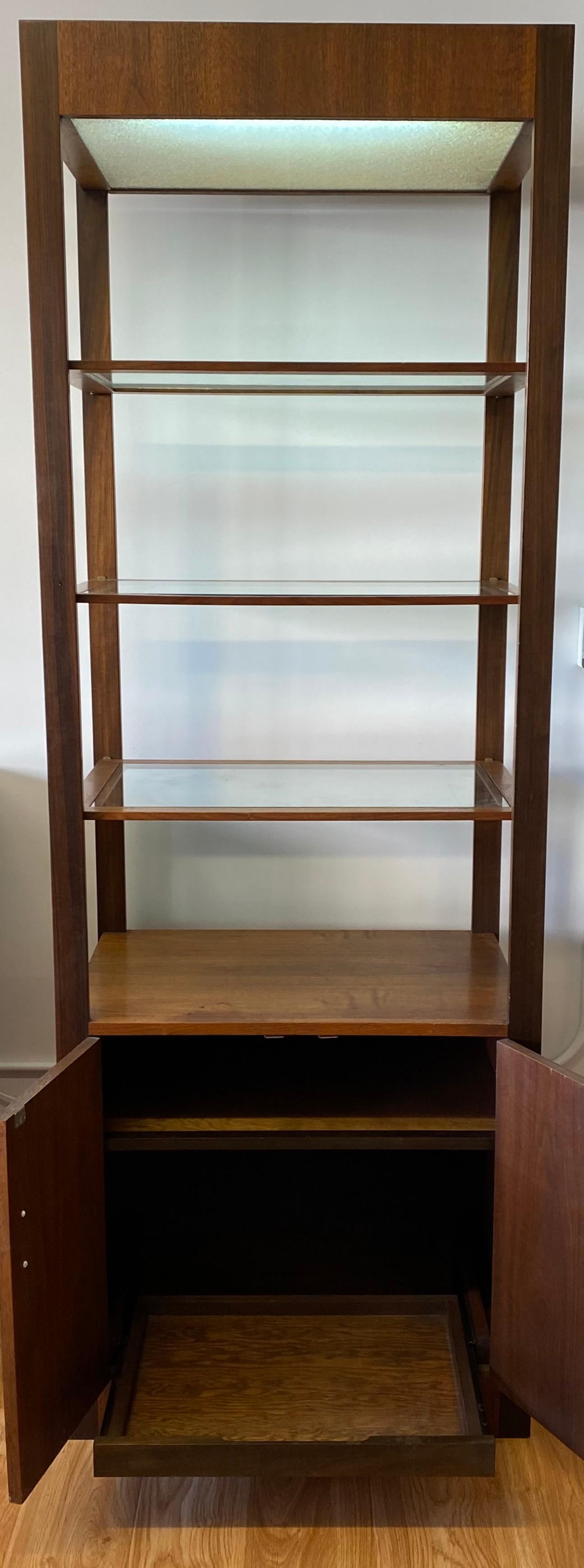 Danish modern walnut cabinet with glass shelves and lighting, circa 1960

Handsome midcentury free standing shelves with lower cabinet and an upper ceiling light

Wired for US outlets

The lower cabinet has a pull-out shelf and mother of pearl