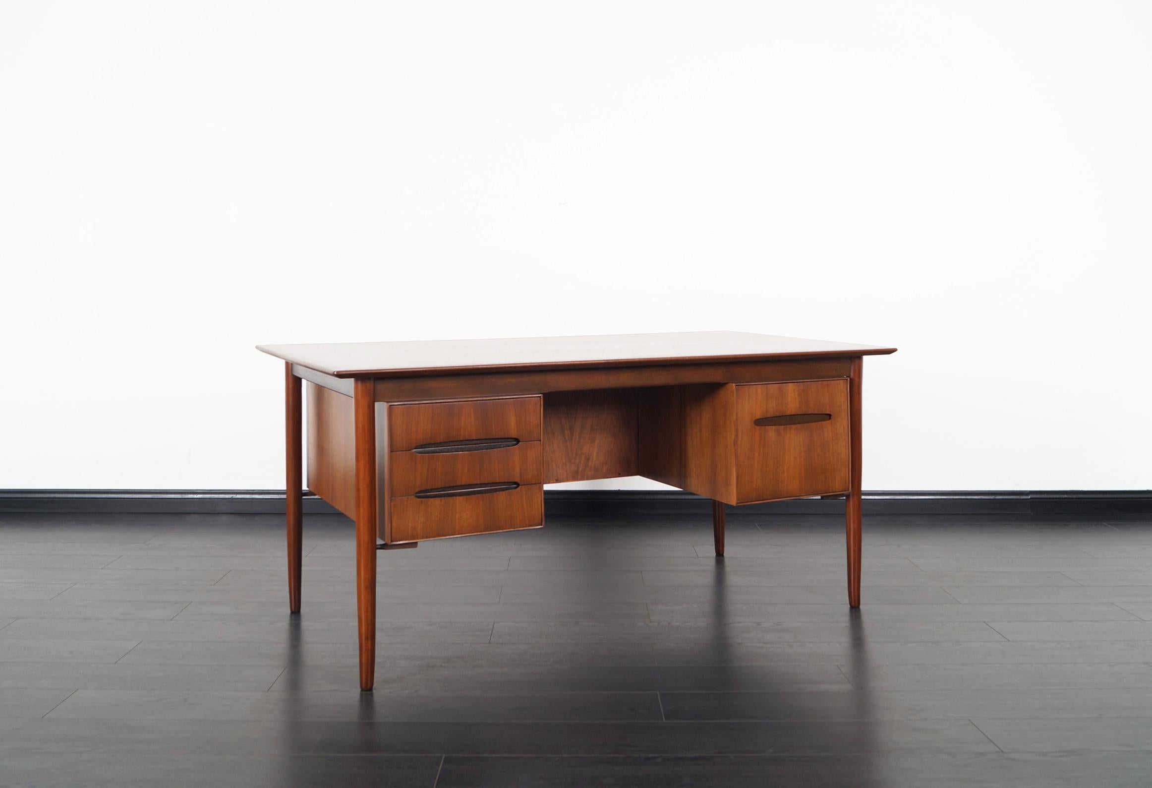 Danish modern walnut desk was designed by Ib Kofod Larsen for Selig. Features three drawers on the left side and one file drawer on the right side. Additional storage space on the back side. Original maker's mark.