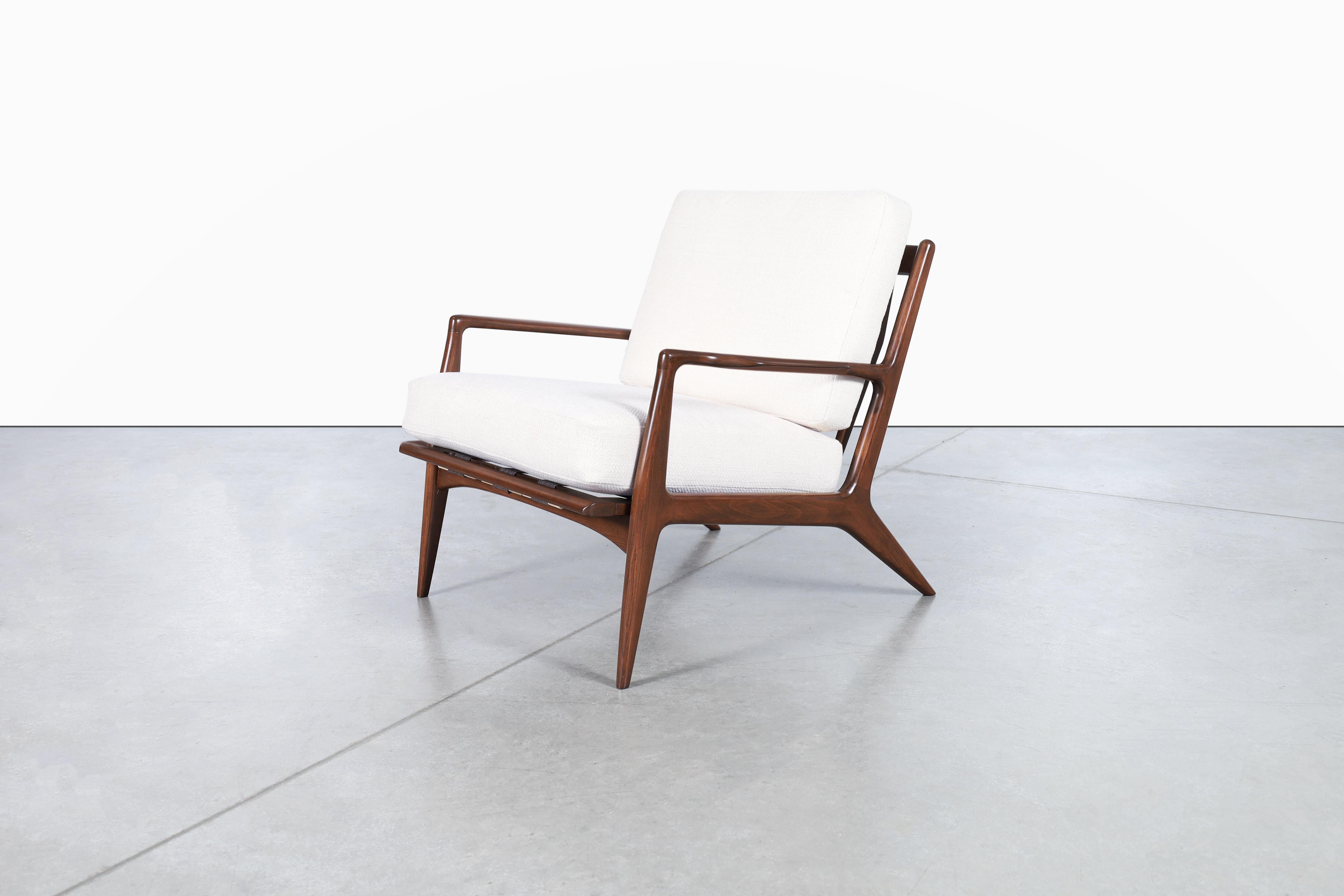 Amazing Danish modern walnut lounge chair designed by architect and furniture maker Ib Kofod Larsen and manufactured by Selig in Denmark, circa 1960s. This fabulous lounge chair features a solid walnut-stained beech frame with angled legs, sculpted