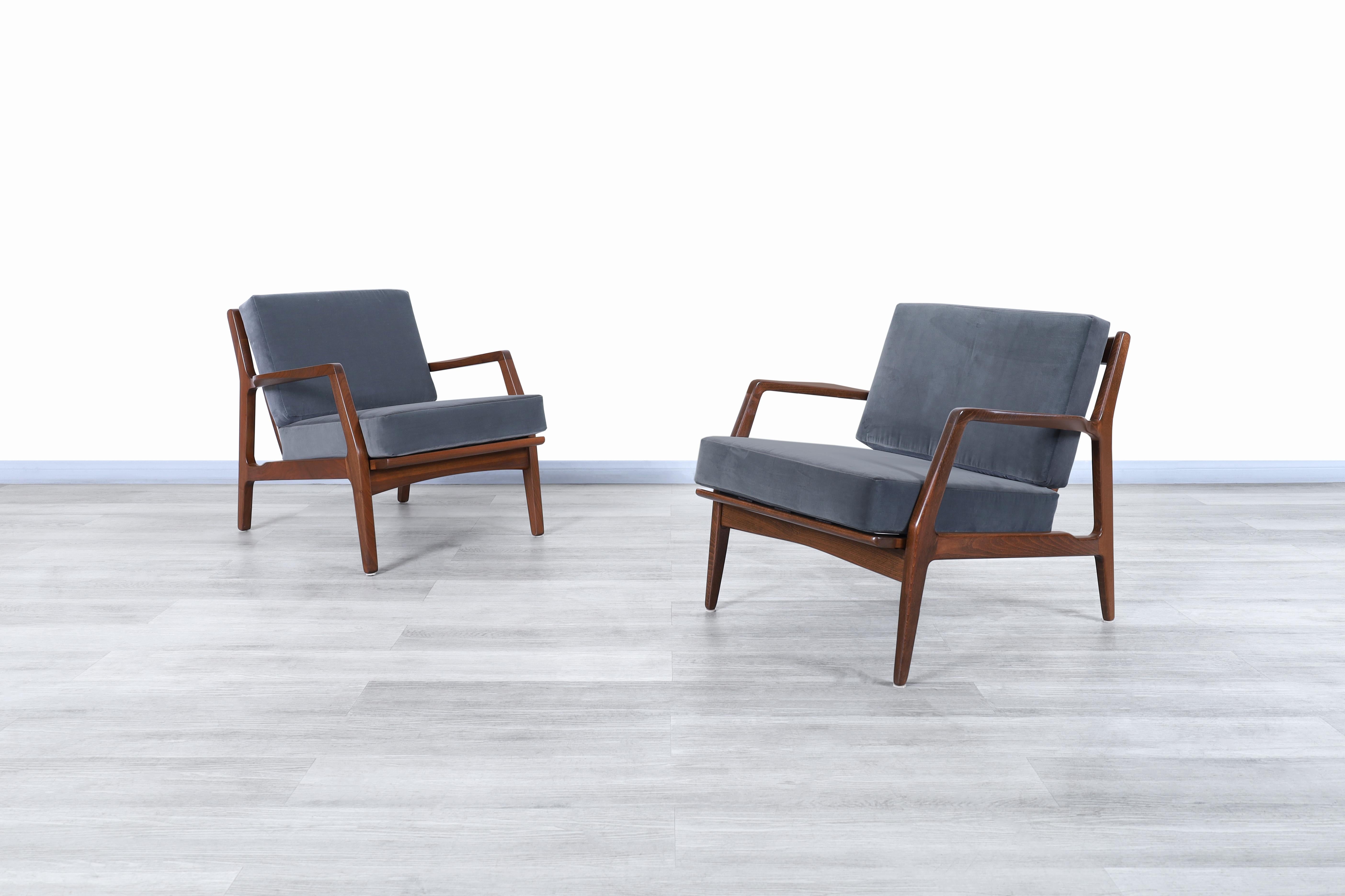 Exceptional Danish modern walnut lounge chairs designed by the iconic Danish designer Ib Kofod-Larsen for Seling in Denmark, circa 1960s. Each chair features a solid walnut frame with angled legs and sculpted slatted backrest, assuring a sleek