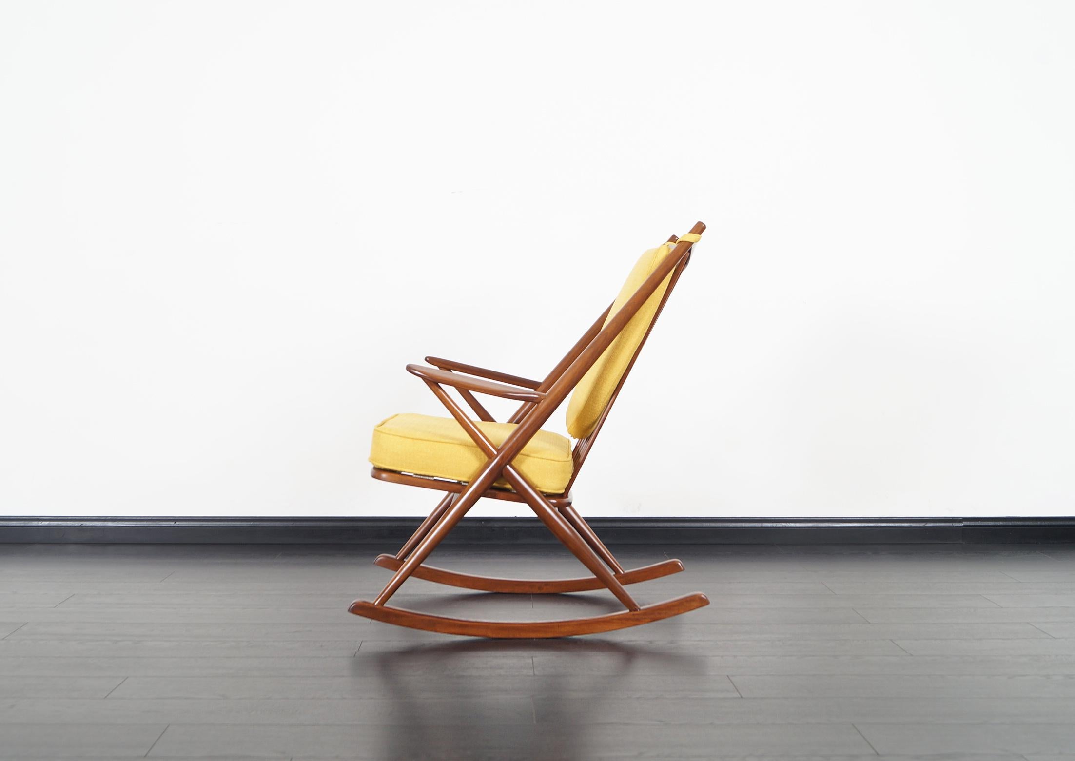 Danish modern rocking chair designed by Frank Reenskaug for Bramin Møbler in Denmark, circa 1960s. Features a solid walnut frame with six vertical spindles on the back side for support. An X-shaped frame that connects the armrests and backrest to