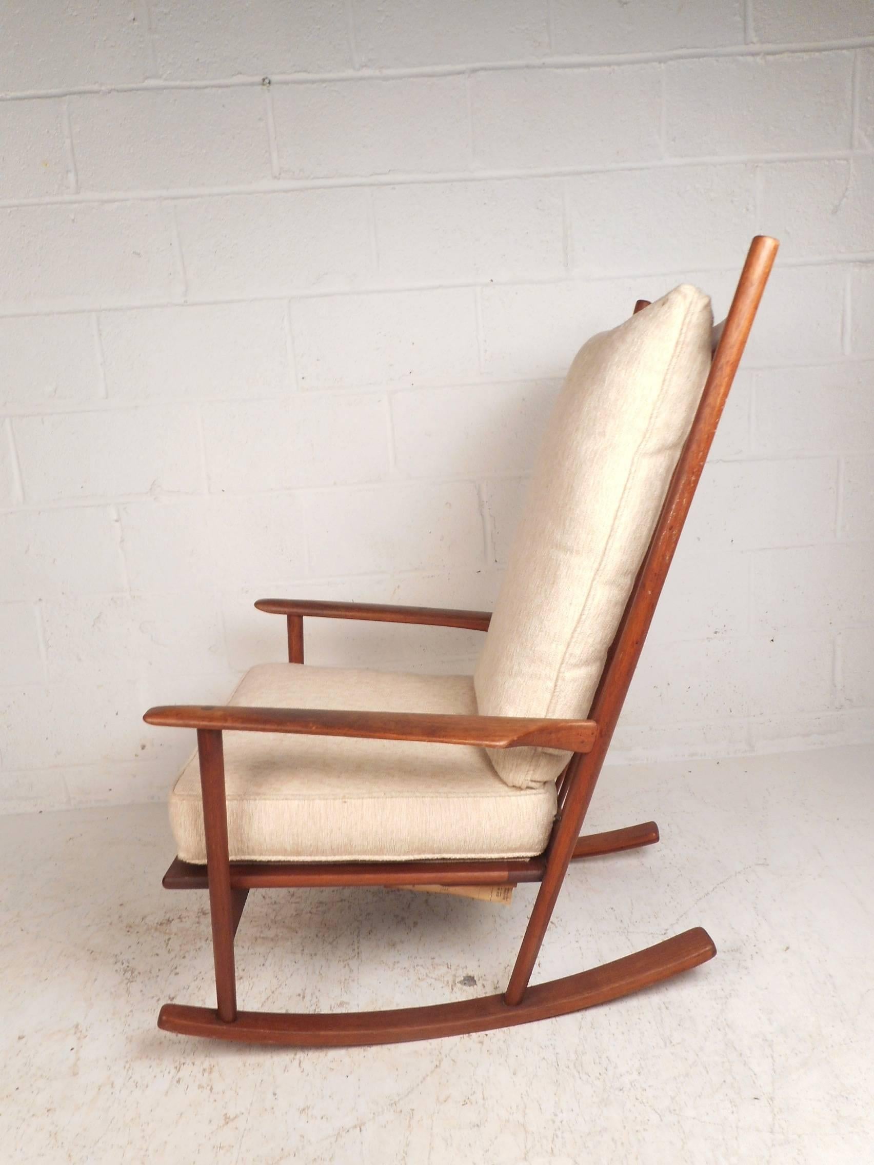 This gorgeous Mid-Century Modern rocking chair features a high spoked backrest with a curved top and sculpted arm rests. An extremely comfortable rocking chair with two overstuffed removable cushions covered in an off-white plush fabric. Sturdy