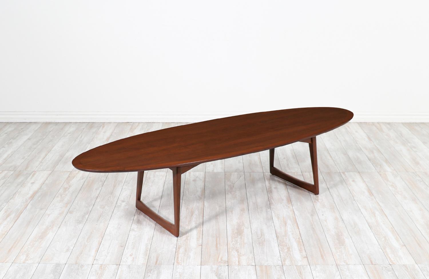 Elegant surfboard style coffee table imported from Denmark by Moreddi circa 1950s. This fantastic design has been meticulously crafted in walnut wood and supported by a sled style and slightly angled sculptural legs. The tabletop shows a richly warm