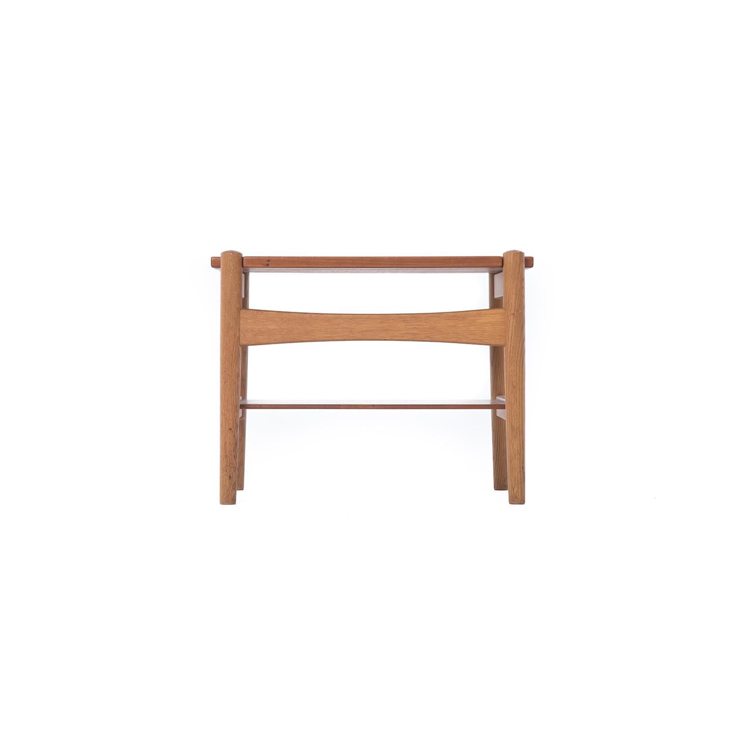 This petite Hans Wegner side table features a teak top and shelf set on an oak frame.