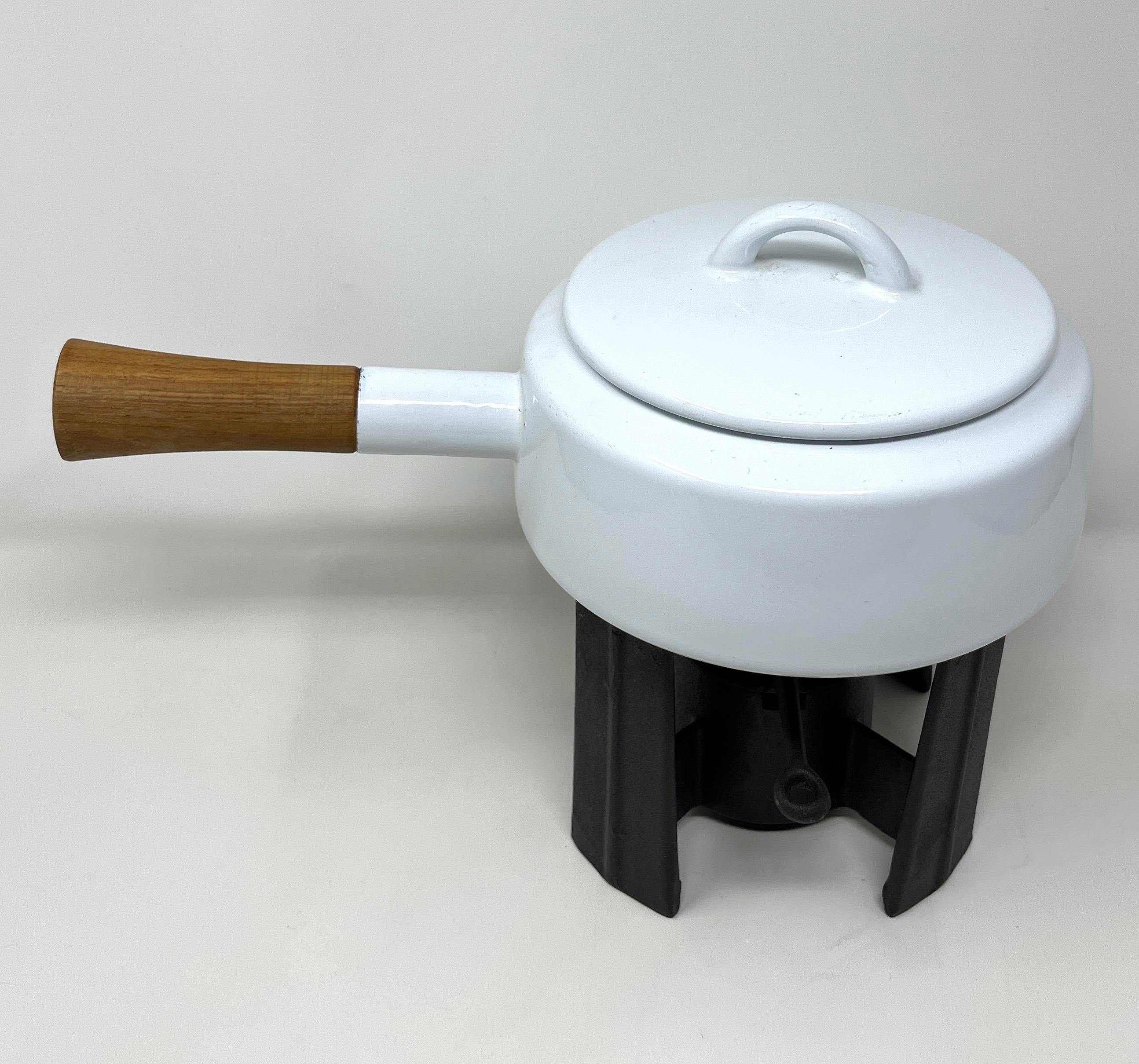 Sculptural, striking, very nice and clean 1970s fondue pot in white enameled finish with white interior, solid teak handle and cast iron base. Designed by Jens Quistgaard and produced by Dansk. The colors white (and black) were introduced in 1971