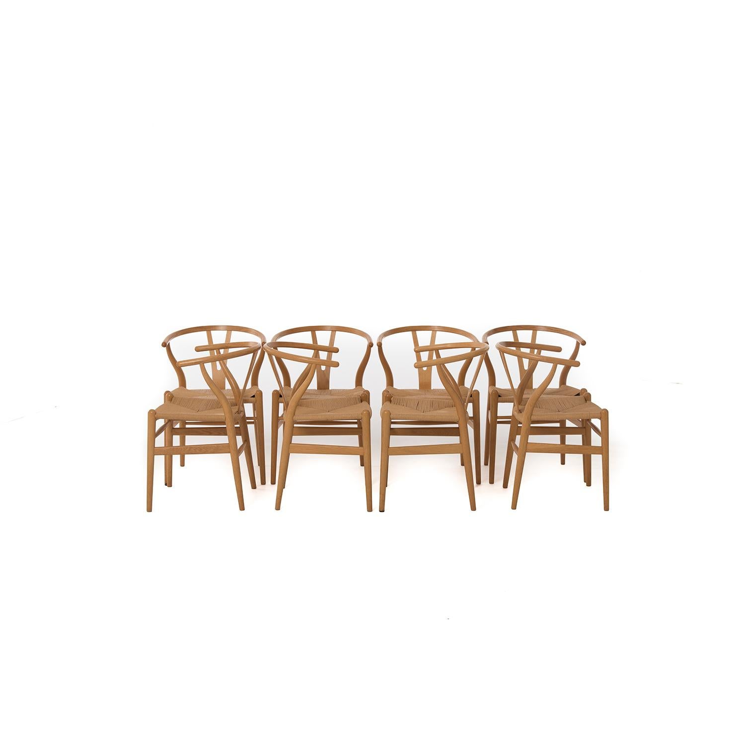 Set of 8 Danish modern wishbone dining chairs by Hans J. Wegner, manufactured by Carl Hansen & Son. Lacquered white oak and Danish cord seats. Seats exhibit some minor faded areas but are overall in very good condition.