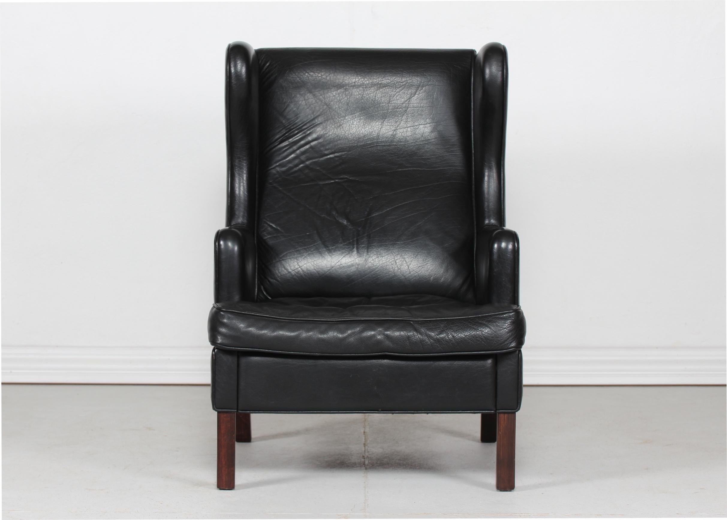 Moderner dänischer Ohrensessel mit Hocker im Stil von Kaare Klint.
Der bequeme Stuhl und Hocker ist mit schwarzem Leder in starker Qualität gepolstert.
Die Beine sind aus dunkel gebeiztem Buchenholz gefertigt.

Messungen Hocker
Höhe 40 cm
Breite 58