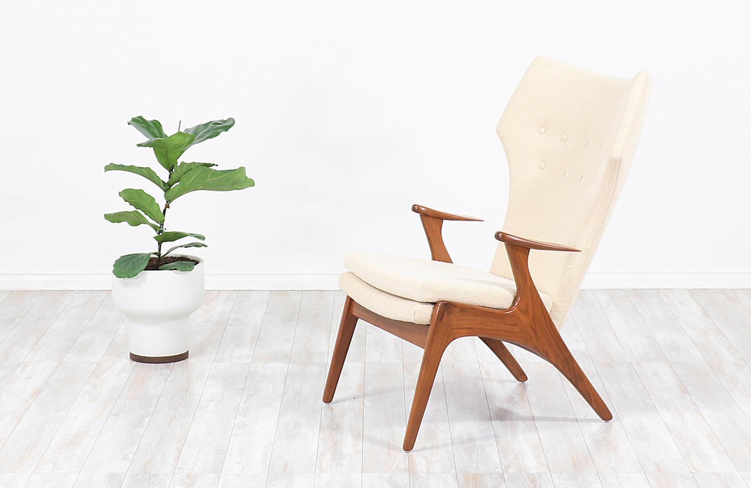 Stylish modern high wing-back chair designed by Kurt Østervig for Rolschau Møbler in Denmark circa 1950s. This gorgeous chair design features a solid walnut wood frame with curved leaf-shaped armrests balancing the design's symmetry while featuring