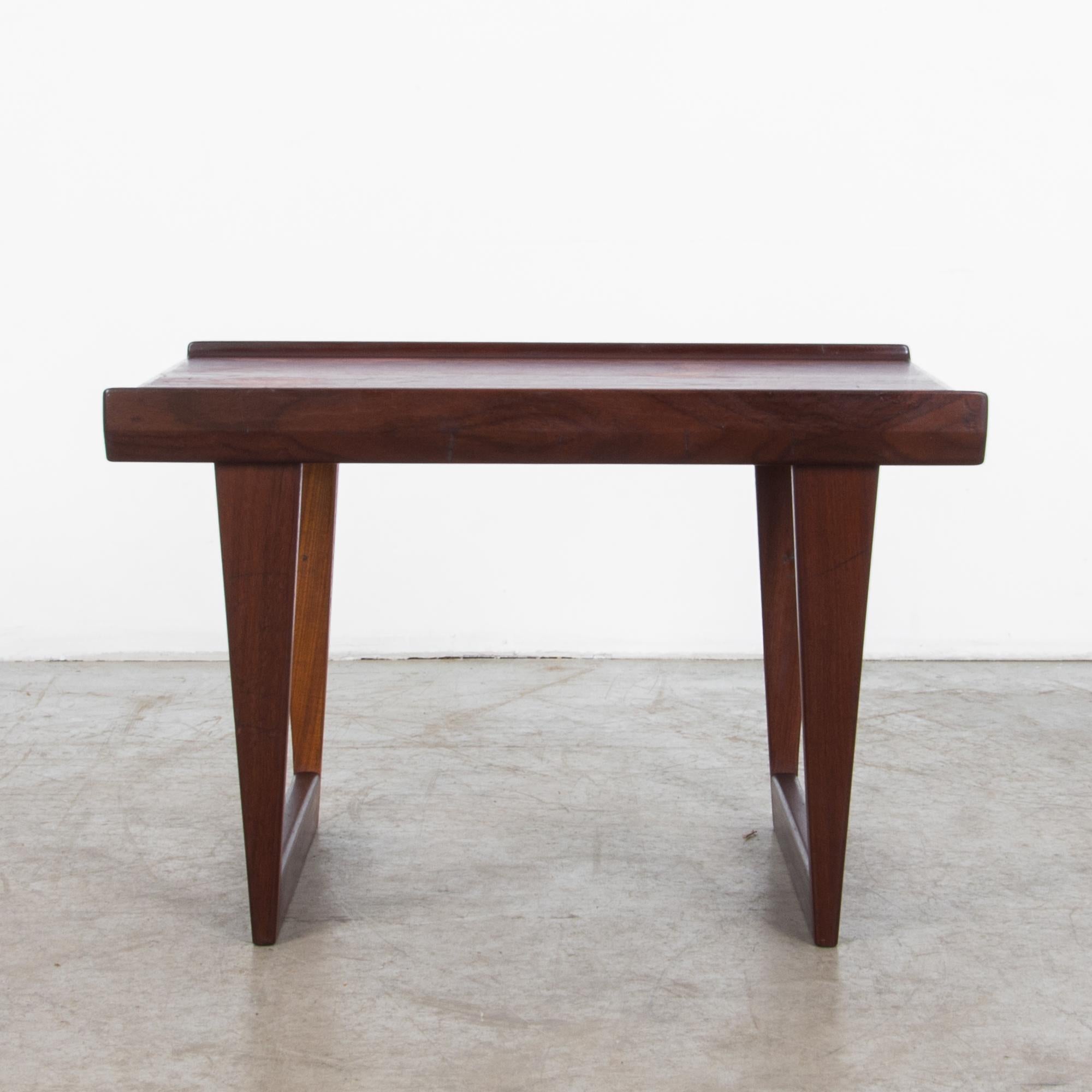 A striking early 20th Century Danish design. This coffee is constructed with geometric legs creating an Escher-like visual effect, while raised and angled veneers along the length emphasize the graceful linearity. The warm finish of the wood and the