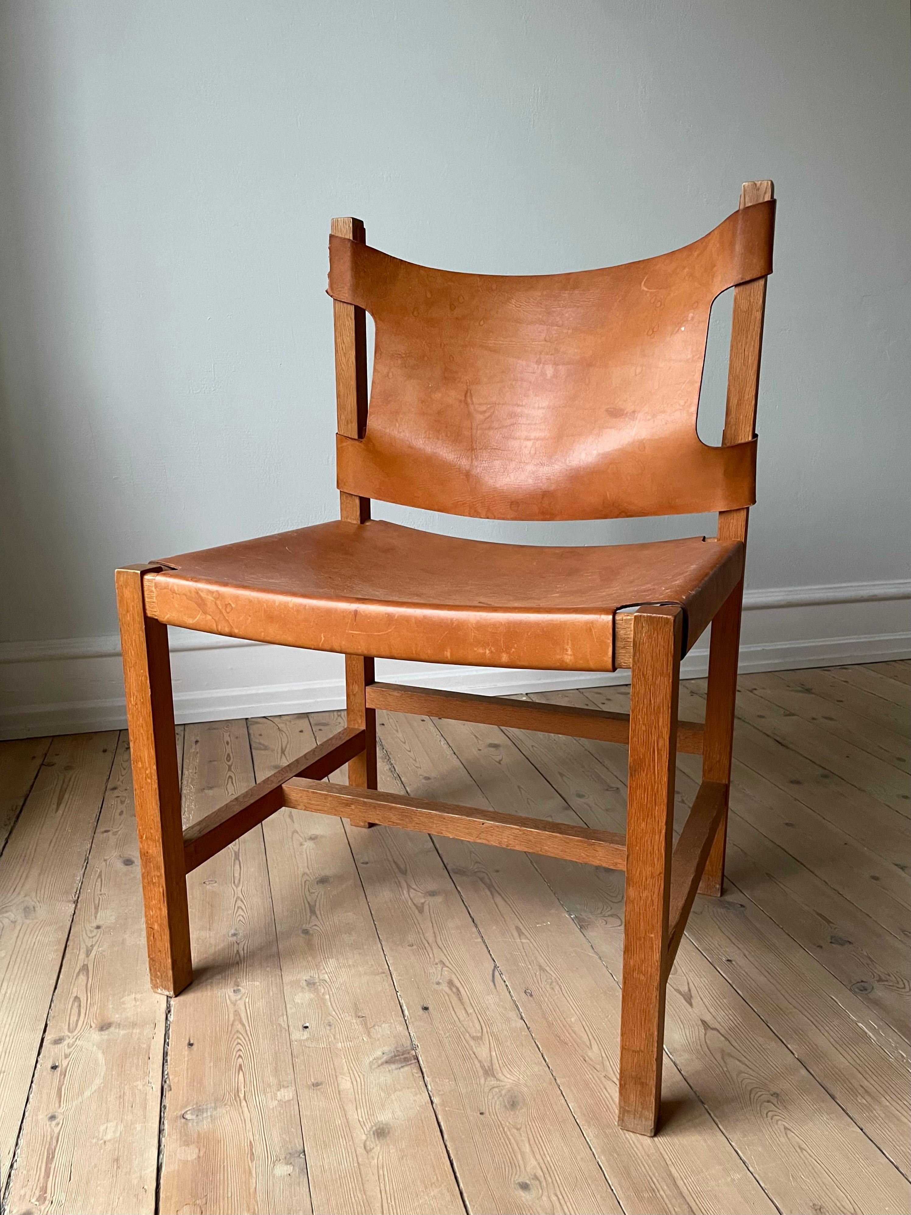 Timeless, classic and functional Danish midcentury modern dining room chair with simple lines and leather seat and leather back. Minimalist and robust silhouette with comfortably soft, warm brown, patinated cognac leather mounted on and draped over