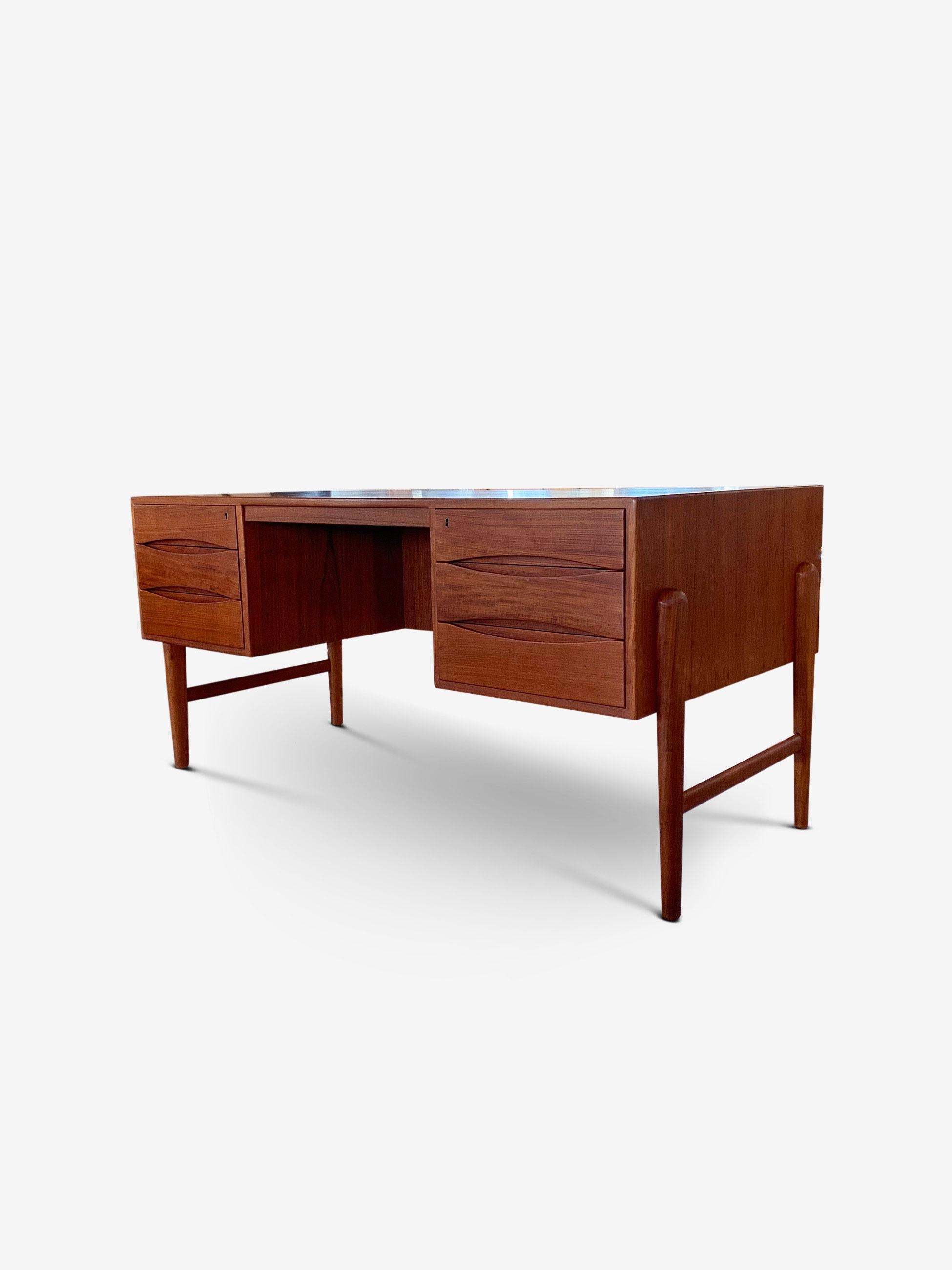 This beautiful double sided teak desk is composed of three drawers on each side with two original locks and keys. The bookcase niche in front allows for easy placement in any room. The eye-shaped recessed pull drawers and tapered legs give this