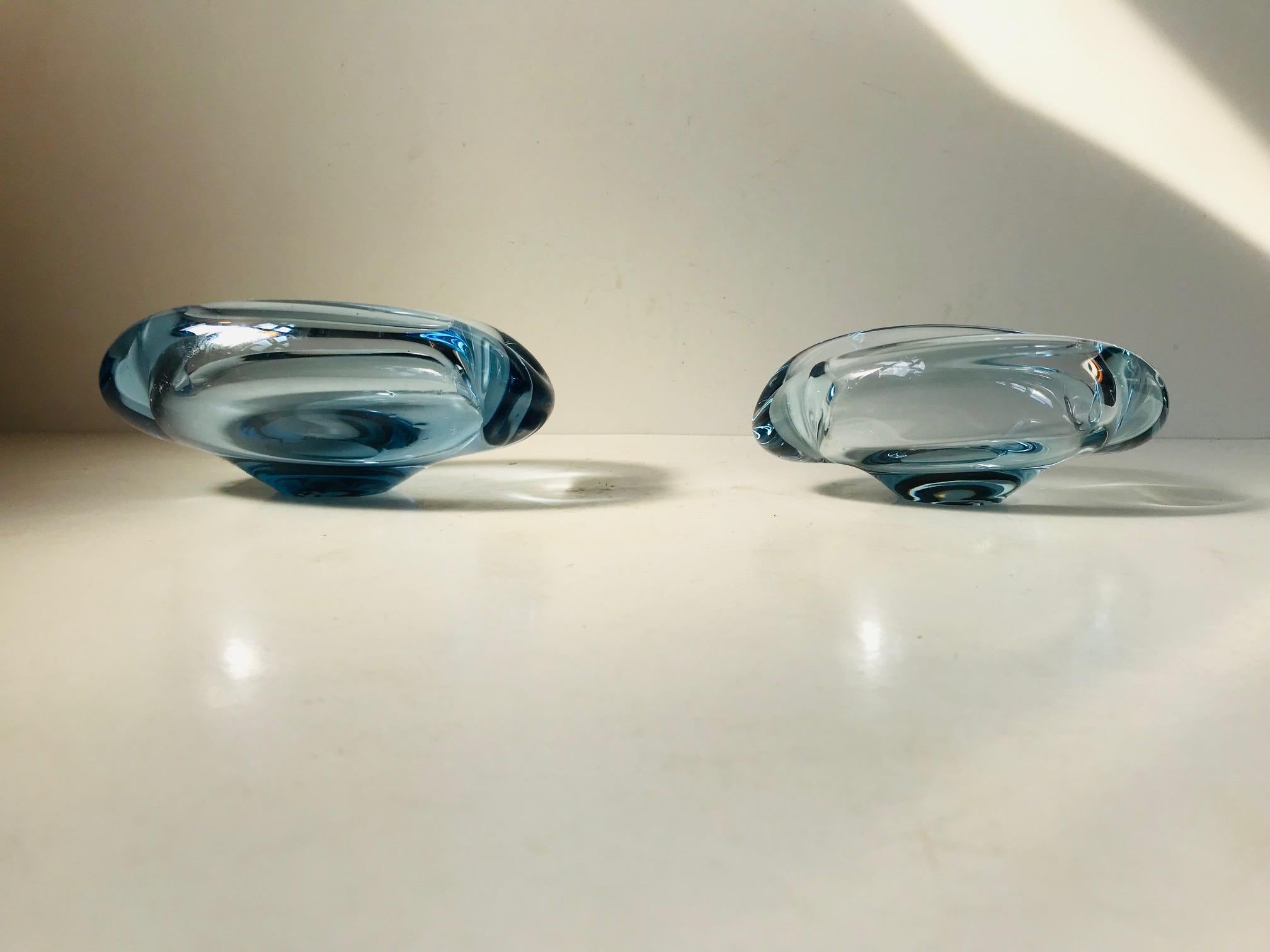 Light blue partially collapsed glass bowls or ashtrays designed by Per Lütken in 1958 and manufactured by Holmegaard in Denmark until 1970. Both pieces are signed and numbered by Per Lütken to the base. Both are in fine intact condition only with