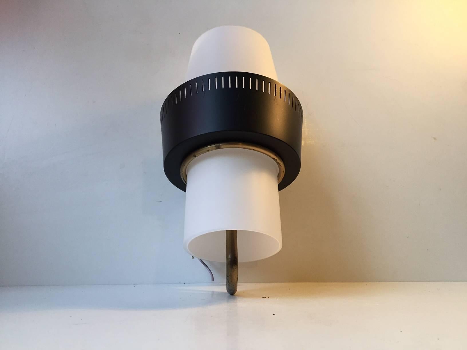 Reminiscent in style and overall quality of Italian manufacturer Stilnovo, this wall light was designed by Bent Karlby and manufactured by Lyfa in Denmark during the 1950s. It is in very good vintage condition with no damage to the white cased
