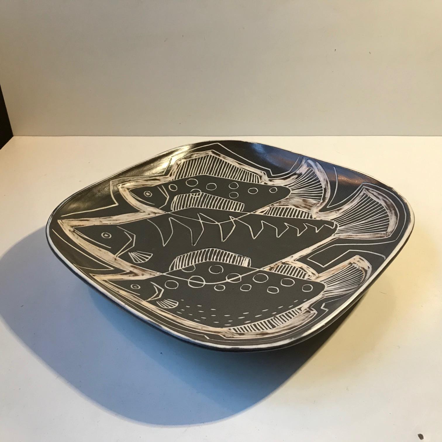 Unique slate black and white dish/bowl decorated with fish. It was designed by the Danish Husband and wife - design duo Eva & Johannes Andersen during the 1960s. The piece is signed to the base. Measurements: W/D: 30, H: 5.5 cm.