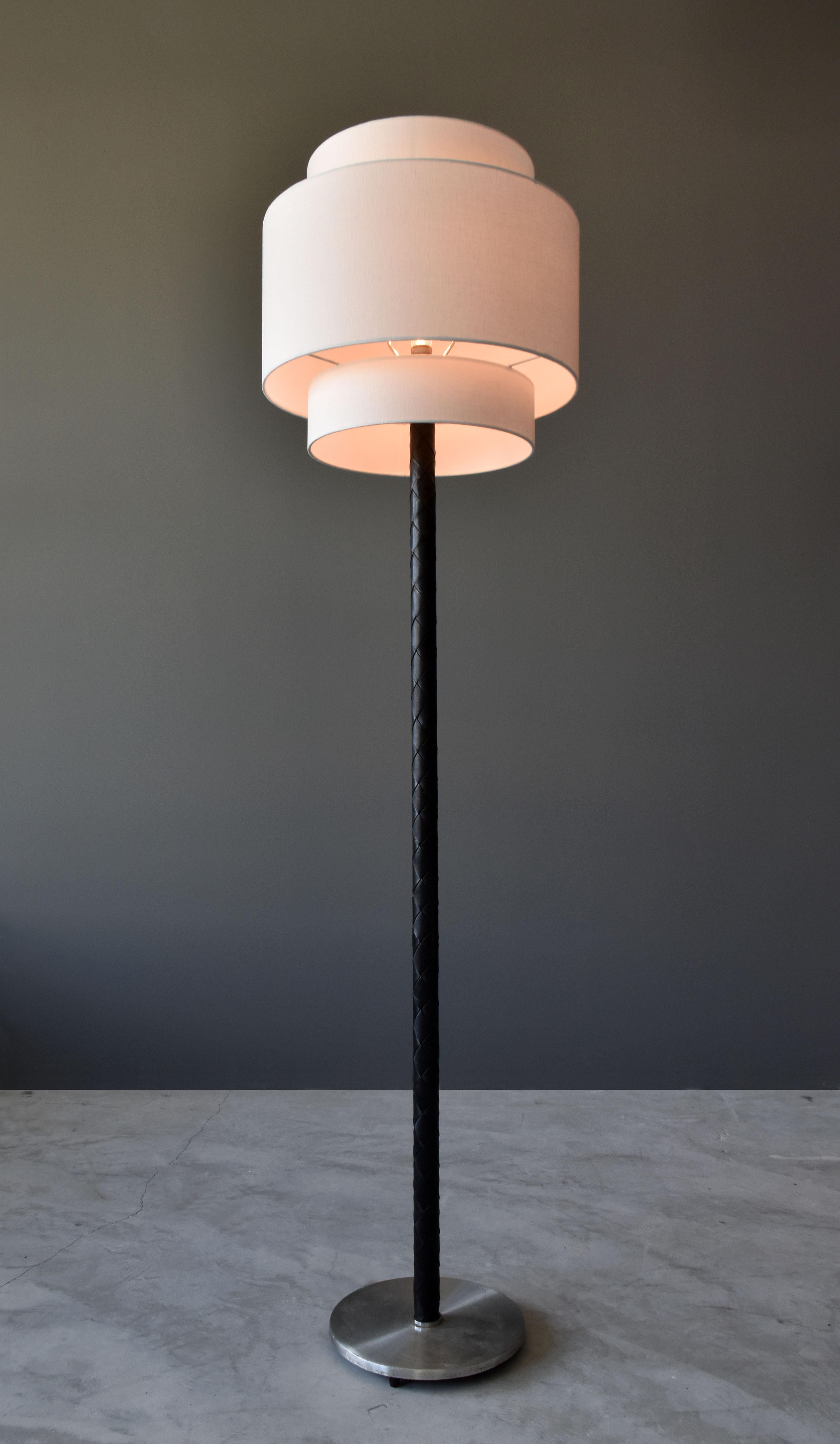 A Danish modernist floor lamp Designed by Jo Hammerborg for Fog & Mørup. Base of stainless steel, rod covered in braided black dyed leather. Handmade two-tier drum screen.

Selection of materials and purity of form is similar to that contemporary