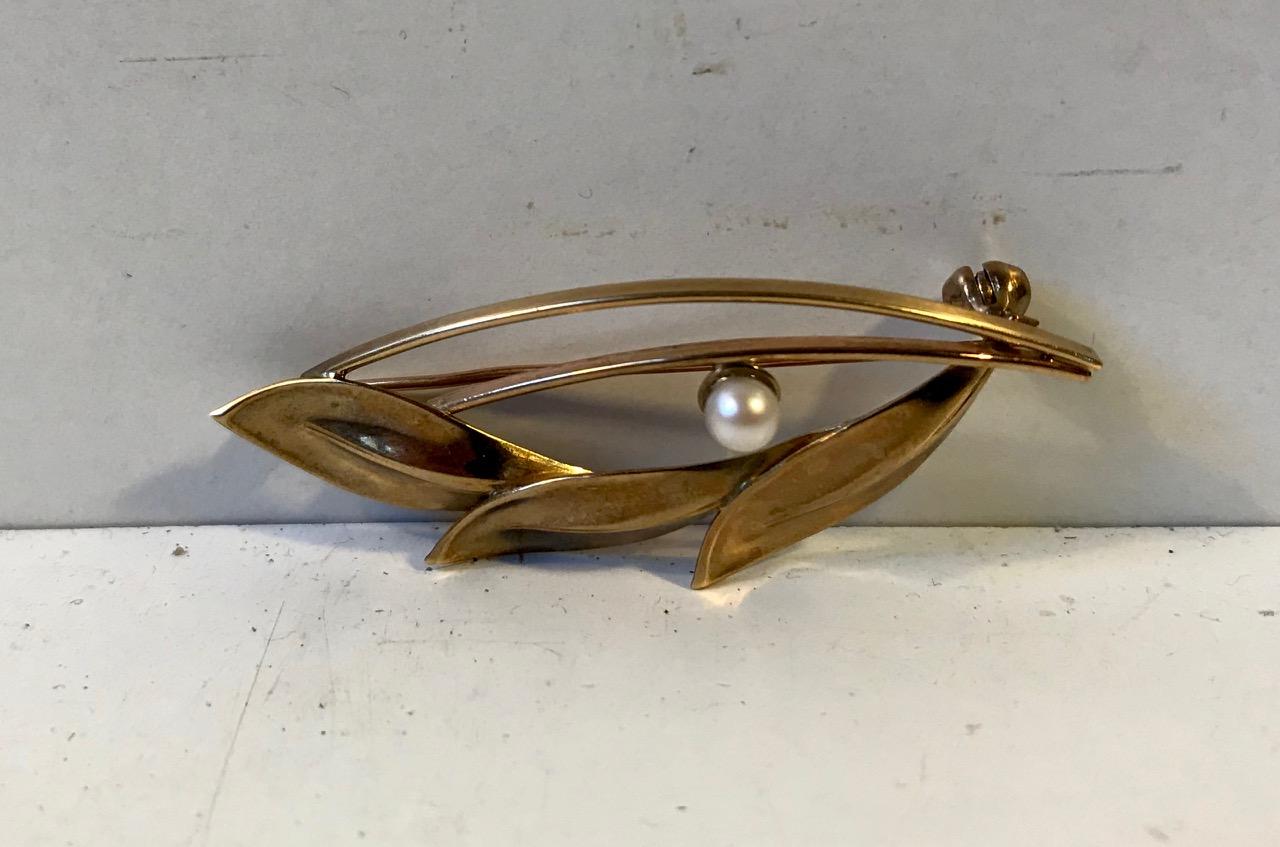 A delicate Danish brooch in shape of a 8-carat gold leaves balanced with Akoya Pearl. Designed by Herman Siersbøl in Denmark during the 1960s. It is stamped HS (the designers initials x 2) which indicates 8-carat.