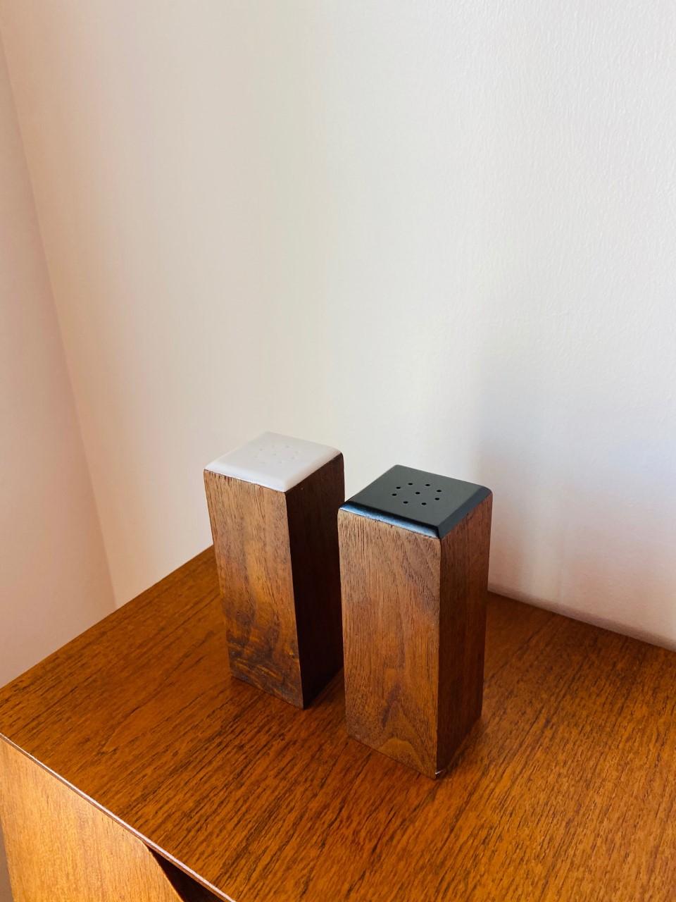 Sculptural and timeless. Beautiful pair of modernist rosewood salt & pepper shakers. Each is beautifully constructed with high design in mind. The elegant lines are tall and clean. The top of the salt shaker is white while the top for the pepper