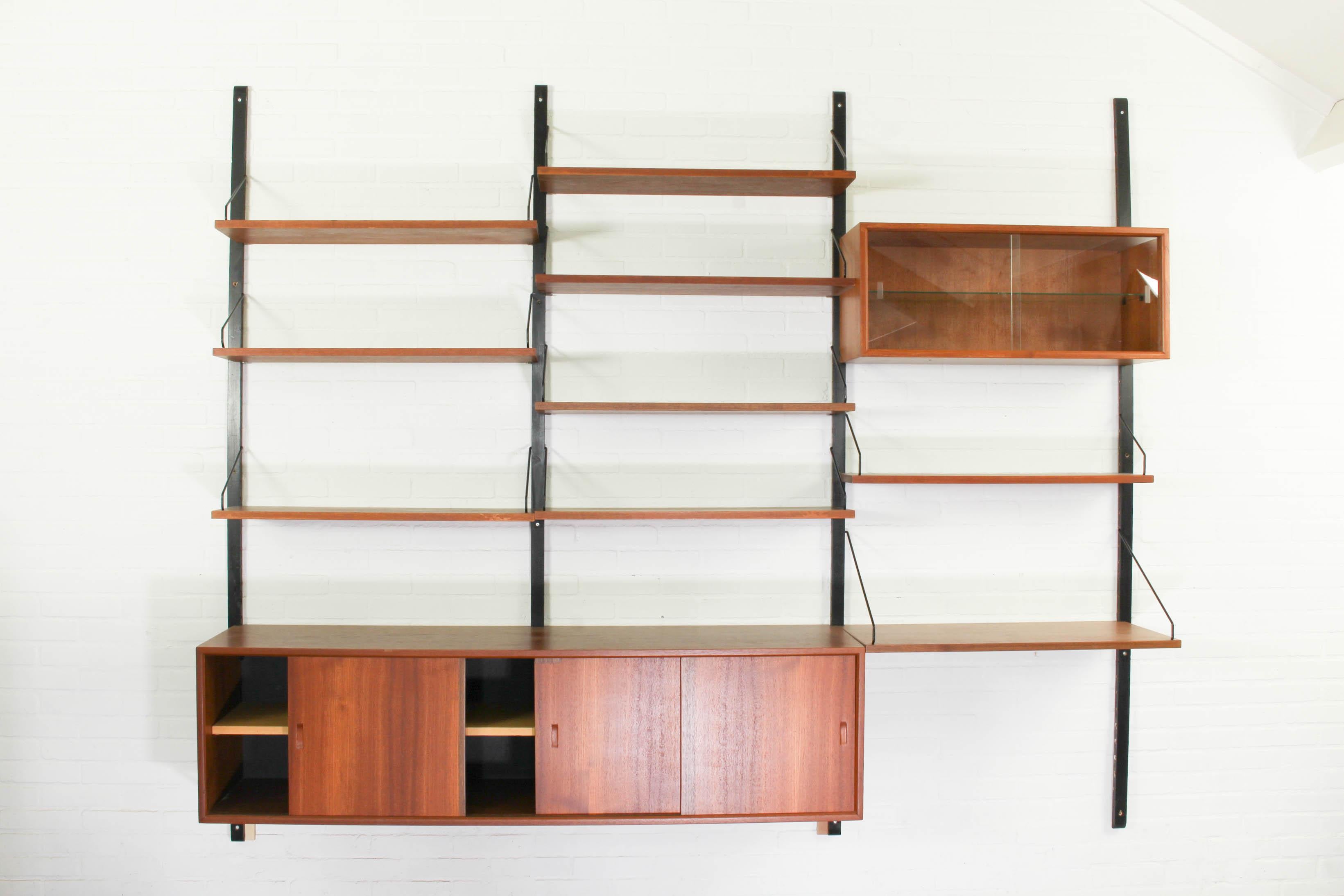 Shelving system in teak designed by Poul Cadovius for Cado, Denmark. This Royal system wall unit consists of extra wide sideboard with 3 sliding doors with 3 small drawers behind one of the doors. It has 8 bookshelves and one deep shelve that can be