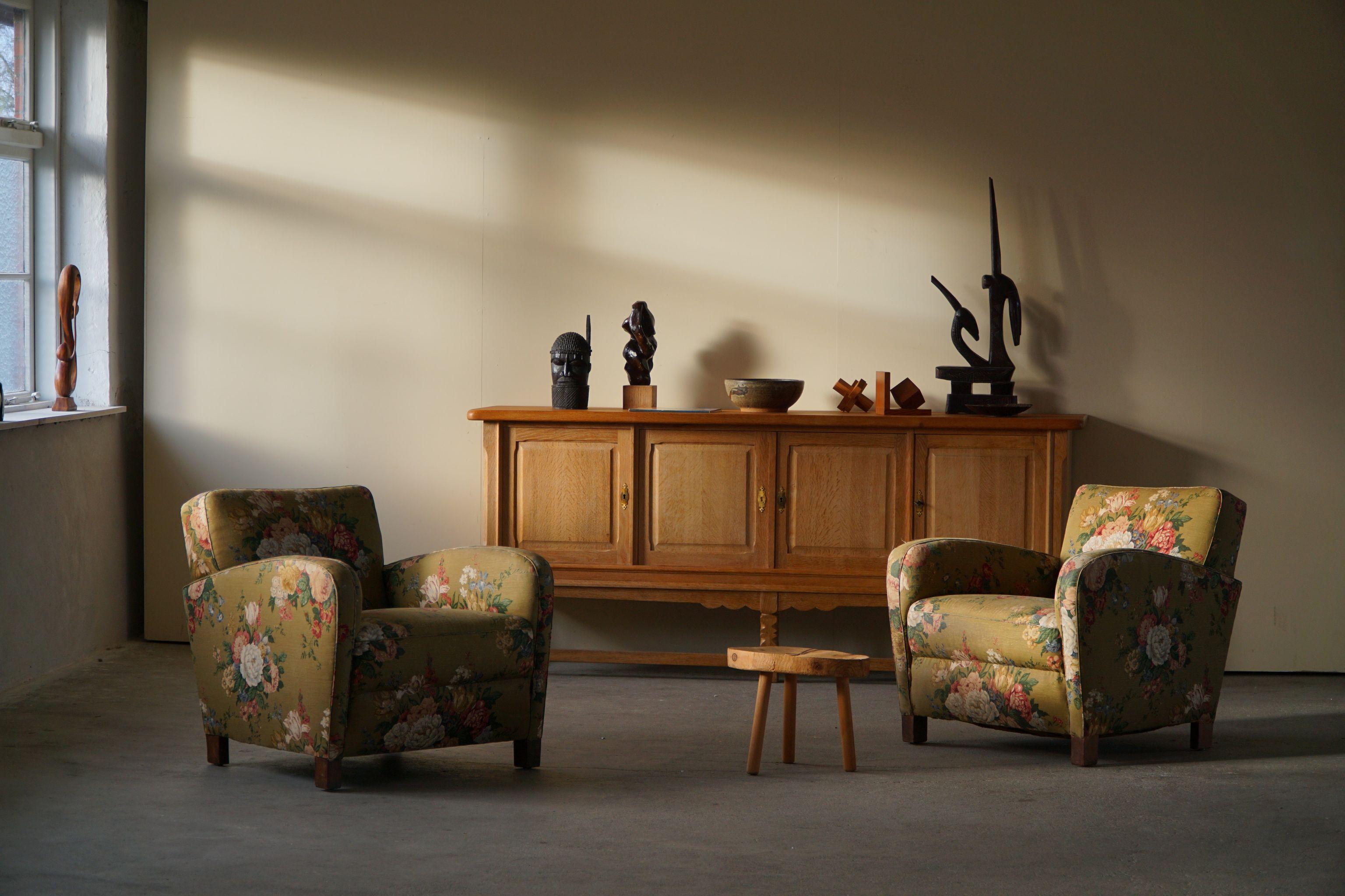 A rare luxurious pair of easy chairs with some beautiful curves. Original fabric with flower motif, made by a skilled Danish cabinetmaker in the 1940s. Very likely made at the Danish company Fritz Hansen. 
A true collectible item from the Danish