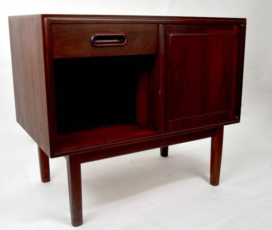 Very good quality Danish modern night table, featuring one drawer, over an open storage cubby, flanked by a door which opens to reveal more storage, as shown. Solid walnut, in dark finish. This case has been professionally refinish, and is in