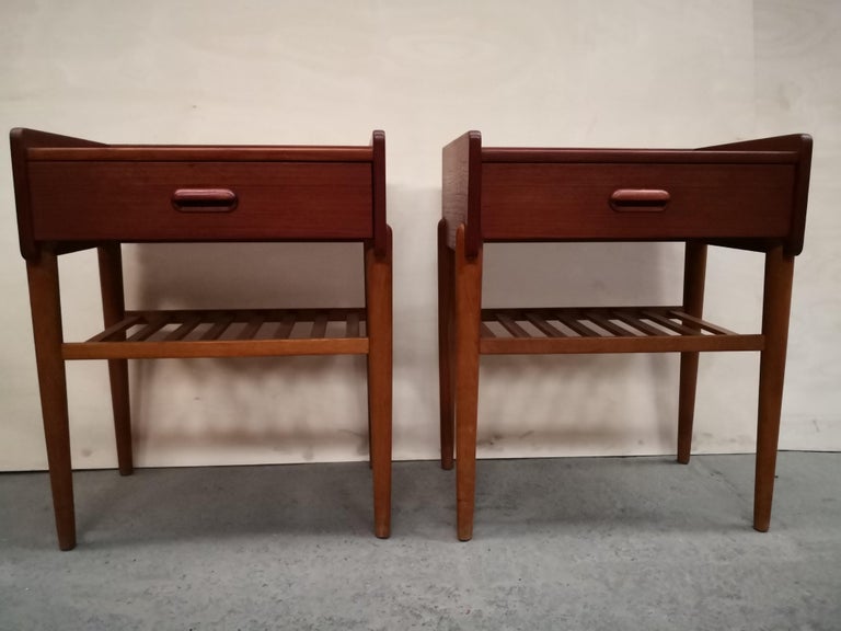 Elegant pair of Danish nightstands feature teak wood and oak legs. Simple in design yet full of style this set will add a degree of sophistication to any bedroom. From legendary danish designer Omann Jun Møbelfabrik.