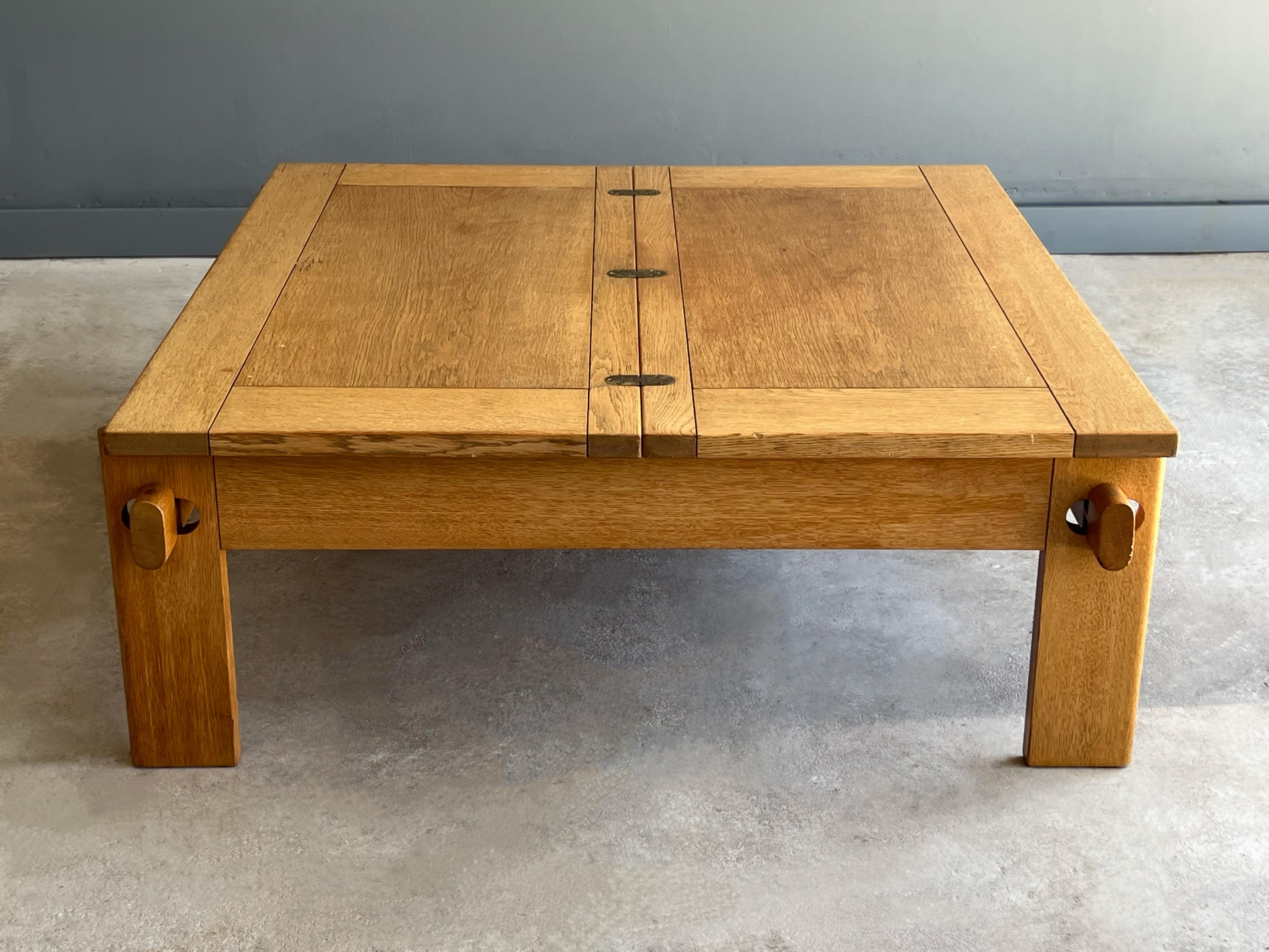 Uncommon Danish coffee table designed by Tage Poulsen, circa 1960s. This table is executed in quarter sawn white oak with brass detailing. Each leg fits into a grove creating a negative space and attractive joint that supports the folding top.
