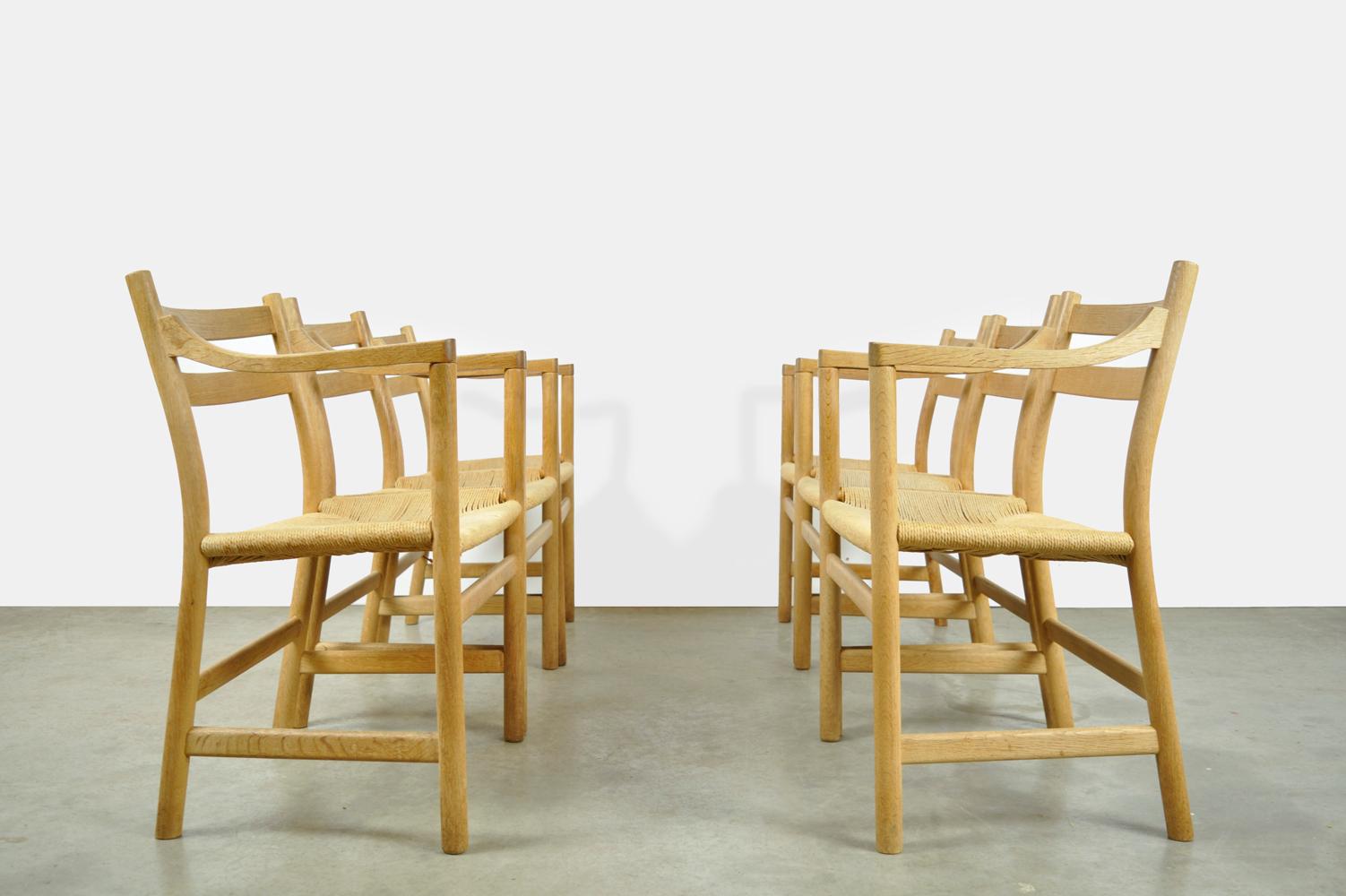 Beautiful set of 6 oak dining table chairs designed by Hans J. Wegner and produced by Carl Hansen & Son, Denmark 1970s. The elegant oak chairs with armrests have a seat made of stretched rope (paper cord). The chairs belong to the first owner who