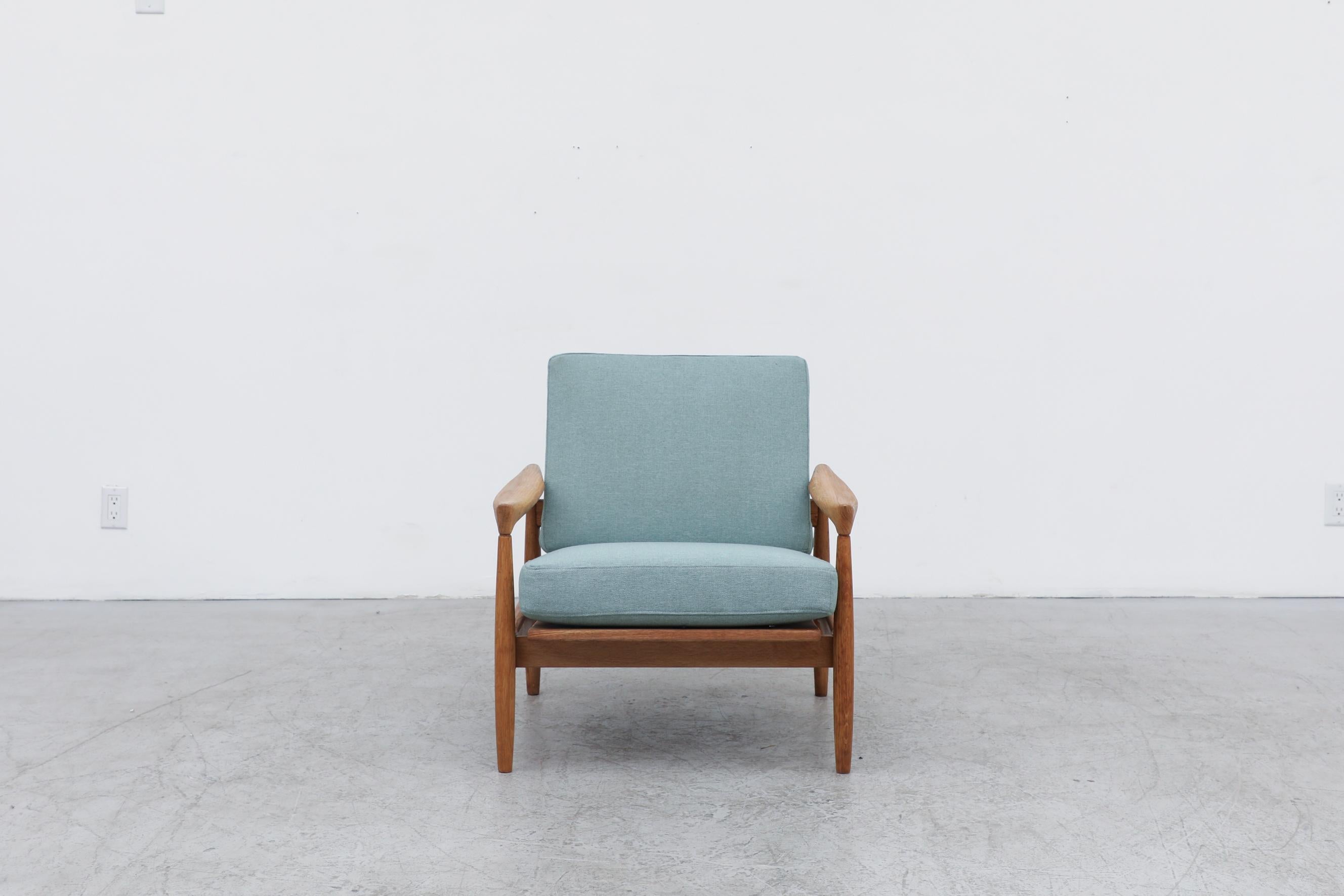 Danish oak lounge chair with organic carved arm rests, exposed slat oak back and light blue upholstered cushions. The cushions were recently reupholstered by previous owner, some wear is consistent with its age and use. The frame is in good original