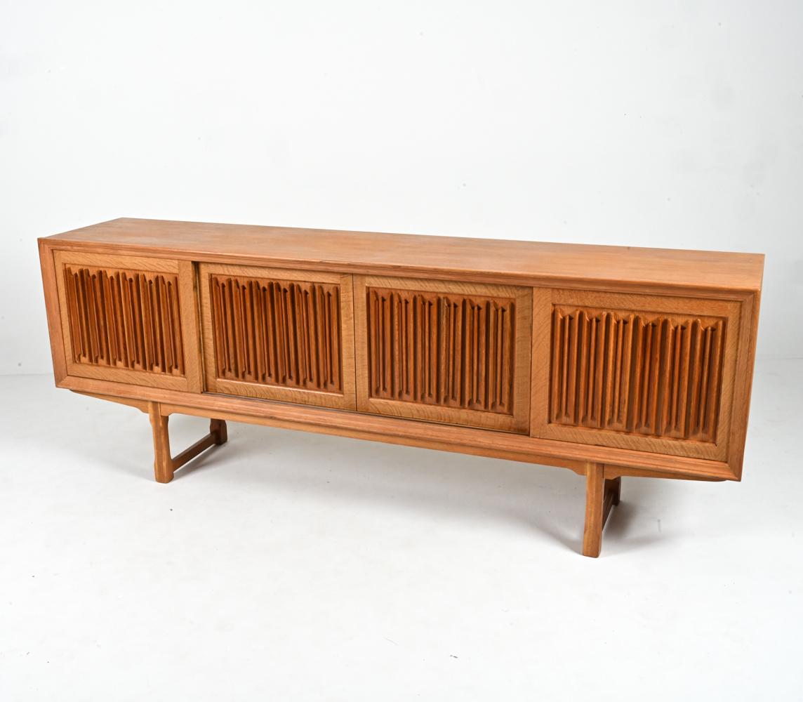 Presenting an exceptional and rare signed sideboard by Henning Kjærnulf, produced by the Danish firm EG Kvalitetsmøbel in the 1960's. The detail that sets this piece apart from the rest is the fabulous carving on its sliding panel doors, a Modernist