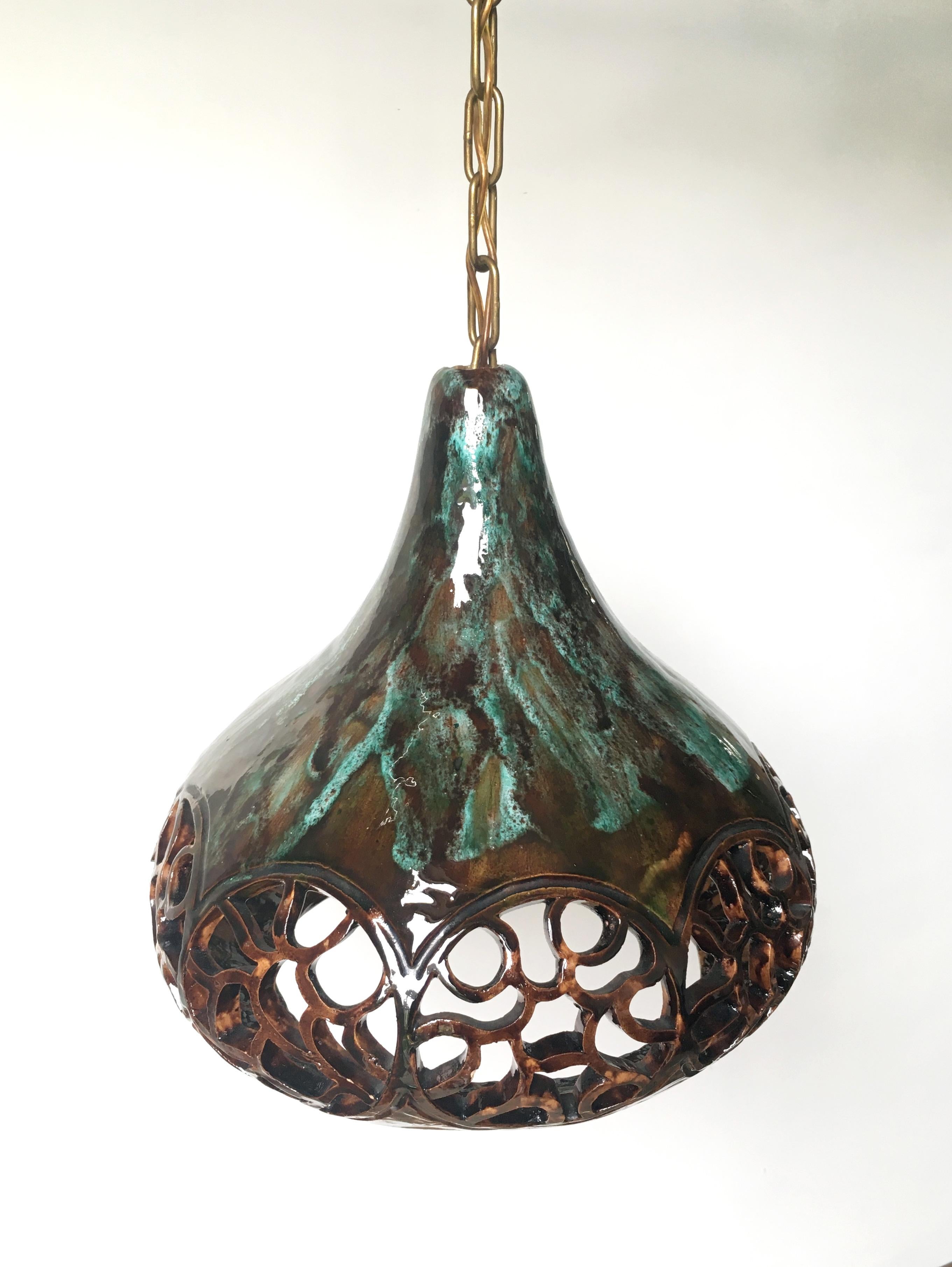 Bell shaped handmade Danish midcentury modern ceramic pendant from the 1960s. Turquoise, dark green, warm browns and earthy colored running shiny glaze with beautiful organic cutouts around the belly of the pendant. Peachy orange glaze on the