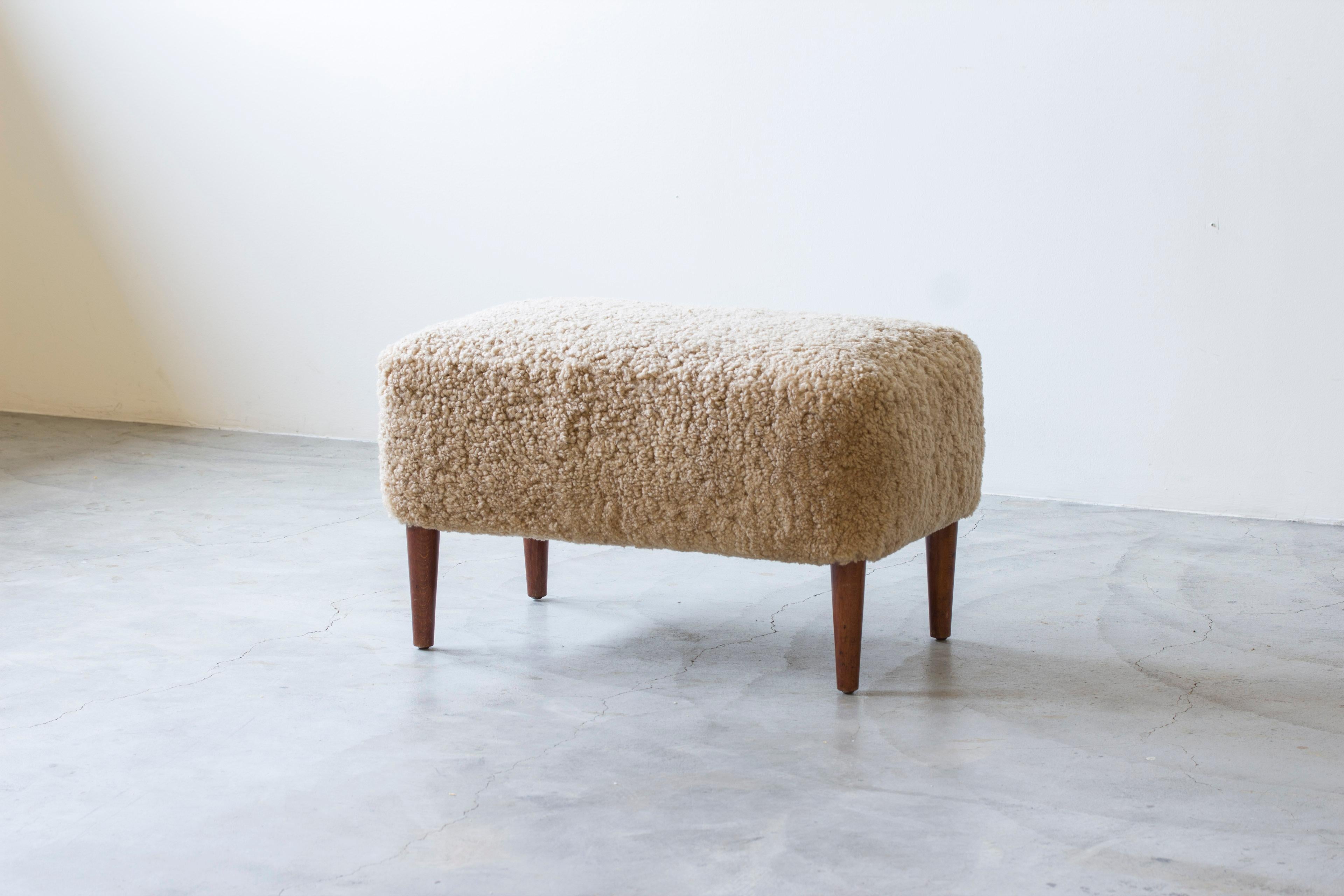Sgabello o pouf di grandi dimensioni  di un ignoto designer ed ebanista danese. Un pezzo di qualità molto bello, con molle a otto vie legate a mano all'interno e una nuova imbottitura in pelliccia di pecora beige chiaro. Gambe affusolate in teak