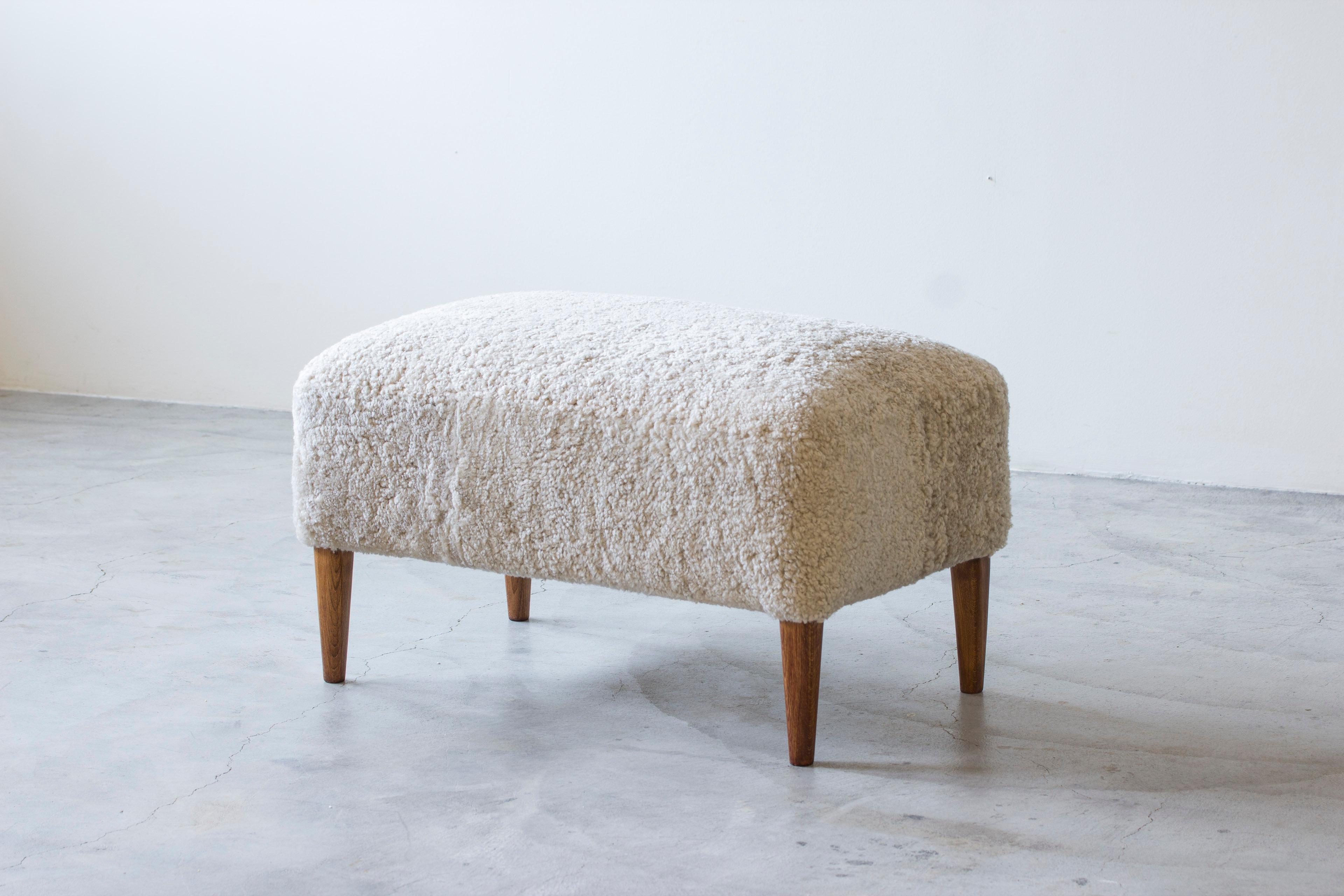 Sgabello o pouf di grandi dimensioni  di un ignoto designer ed ebanista danese. Un pezzo di qualità molto bello, con molle a otto vie legate a mano all'interno e un nuovo rivestimento in pelle di pecora color crema. Gambe affusolate in teak