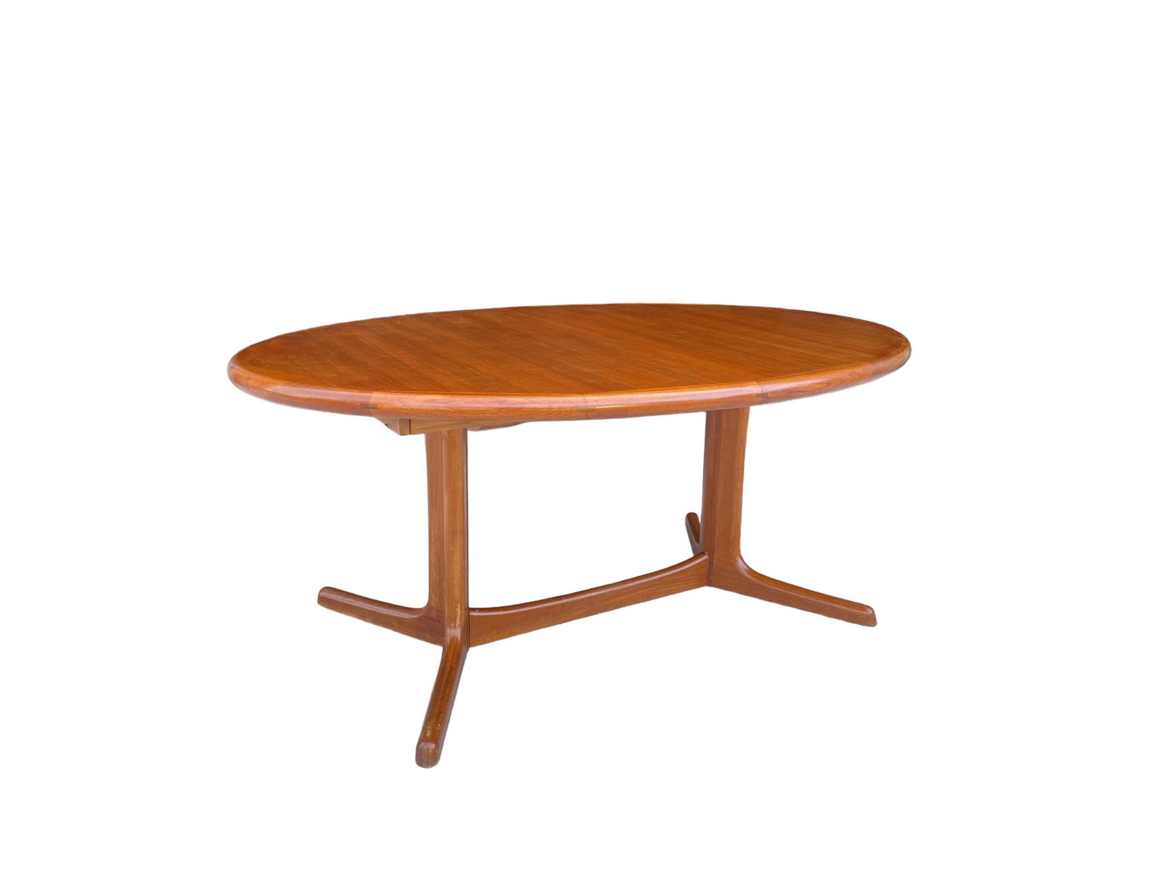 Danish Teak dining table by Dyrlund. This oval table features old growth teak grain and rich color. The tapered oval end and banded edges add a touch of elegant design. Two leaves can extend the table to a maximum of 100 inches. Excellent example of