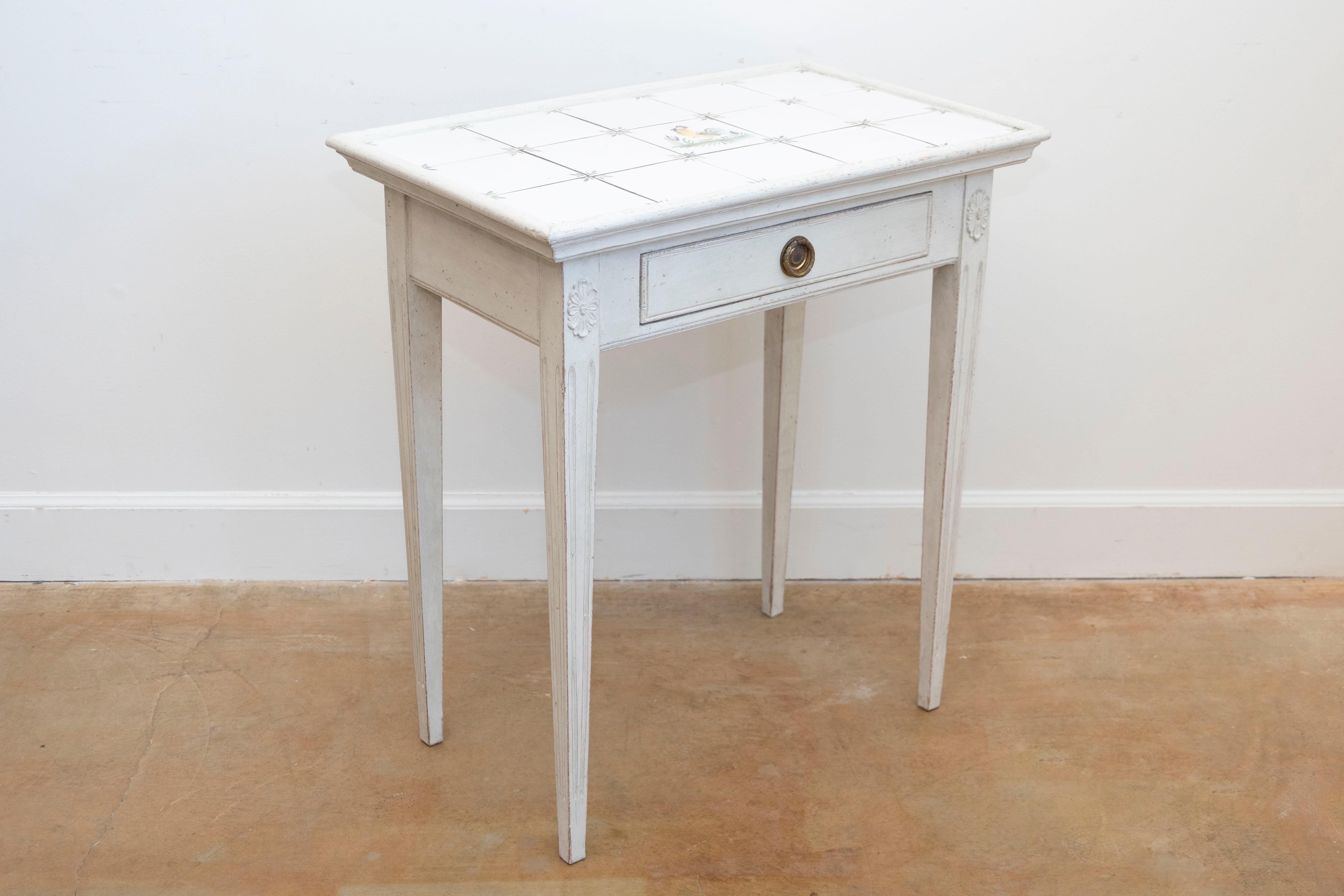 Table d'appoint danoise en bois peint du 20e siècle, avec un plateau en carreaux et un seul tiroir. Créée au Danemark au cours du XXe siècle, cette table d'appoint présente un plateau rectangulaire dont le centre est orné d'un motif de coq. Le