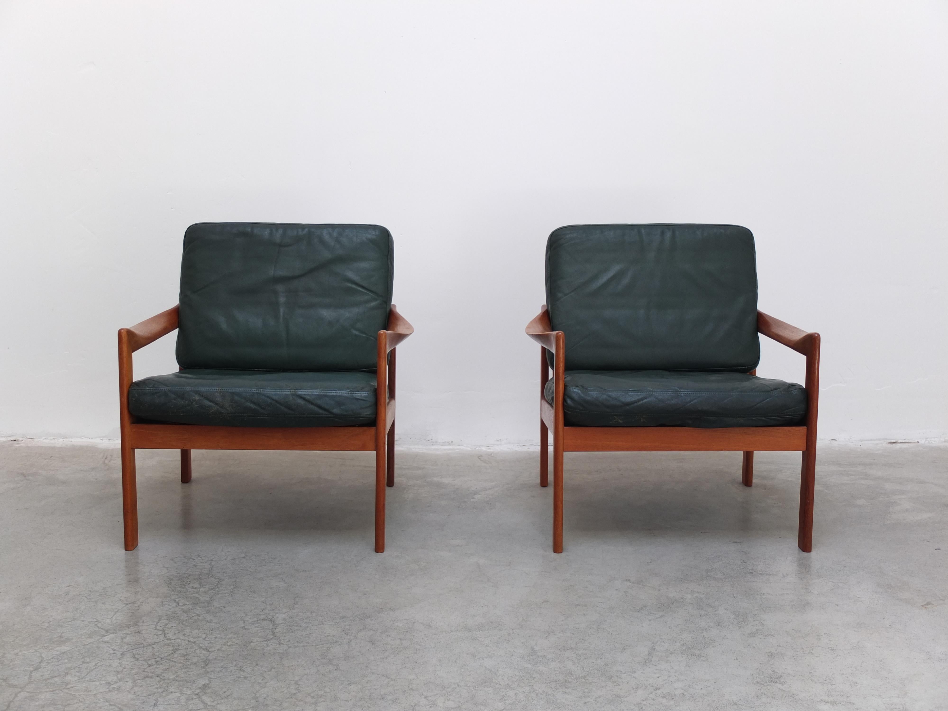 Fabuleuse paire de chaises faciles conçues par Illum Wikkelsø vers 1960. Structure en teck massif avec de magnifiques accoudoirs sculptés. Cette paire a encore les coussins d'origine en cuir vert, ce qui est rare. En bon état avec de petites traces