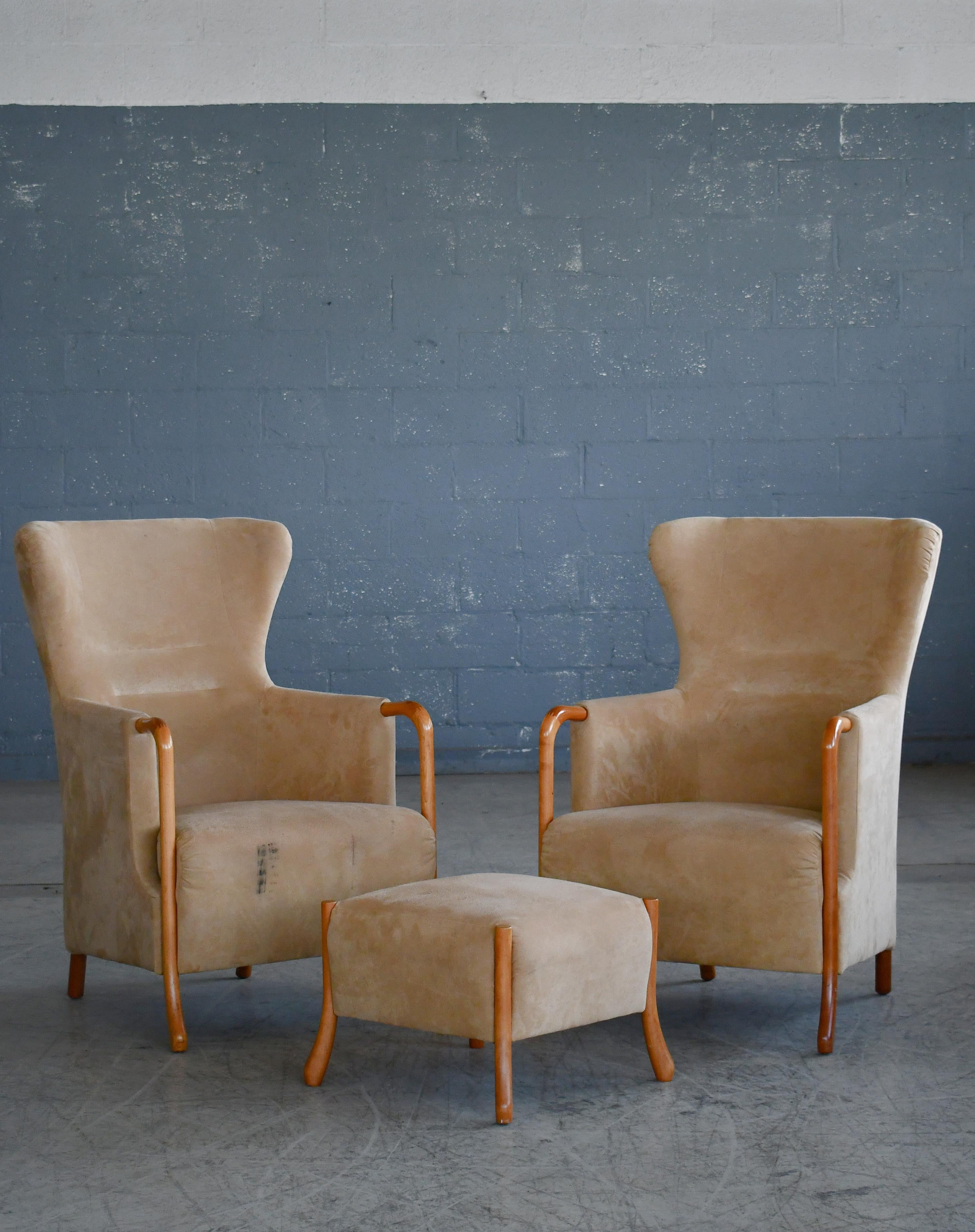 Classic pair of Danish wingchairs with ottoman designed by  Jacob Berg in 1997 for renowned Stouby Mobler.  A classic wing chair and footstool in modern design. Very comfortable and sturdy. Constructed in molded foam around a tubular frame of steel.
