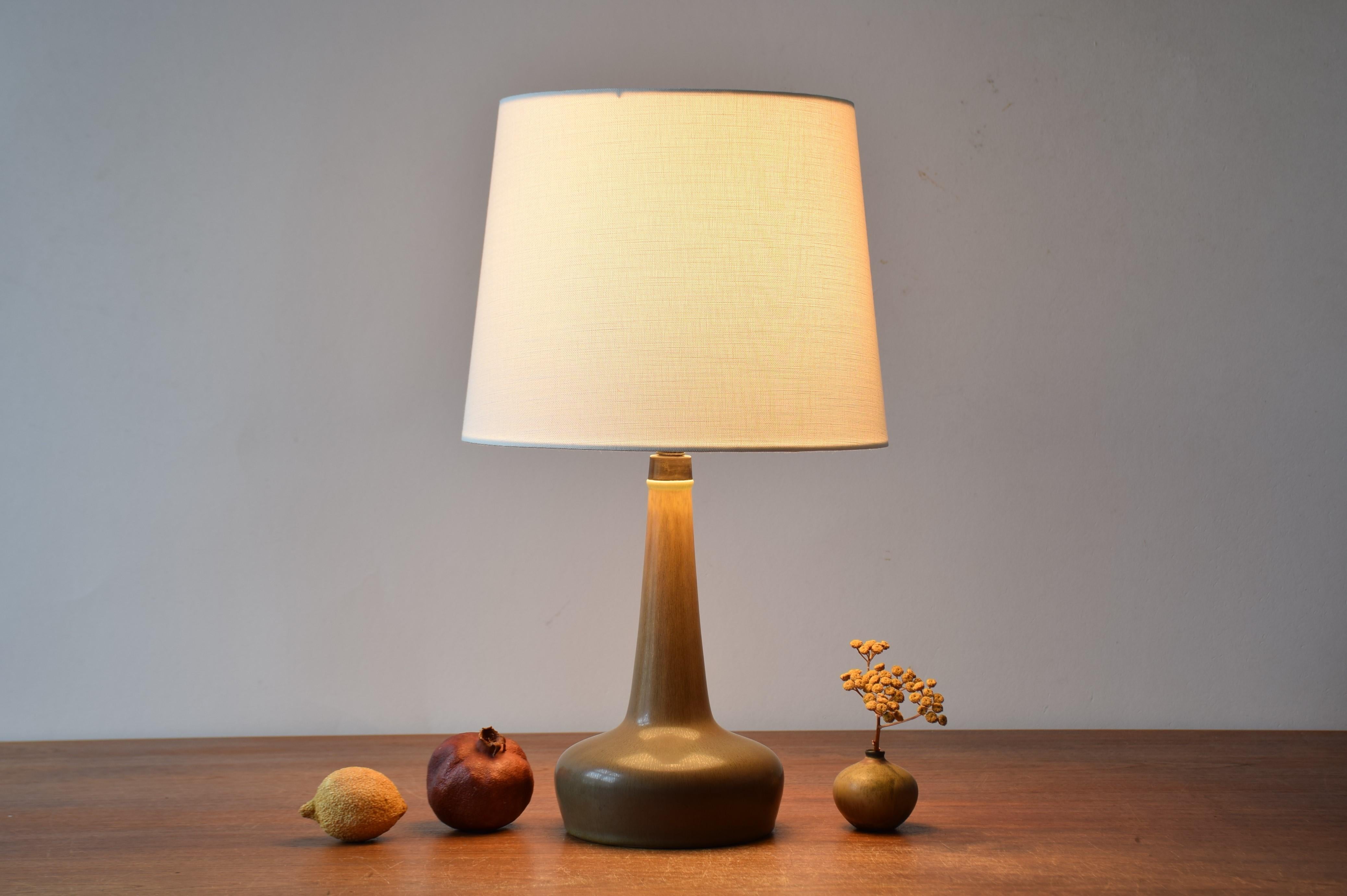 Lampe de table Palshus / Le Klint avec glaçure brun lièvre et plateau en laiton patiné.
Cette lampe a été conçue par Esben Klint et fabriquée au studio de céramique danois Palshus pour le fabricant danois de lampes Le Klint. Fabriqué dans les
