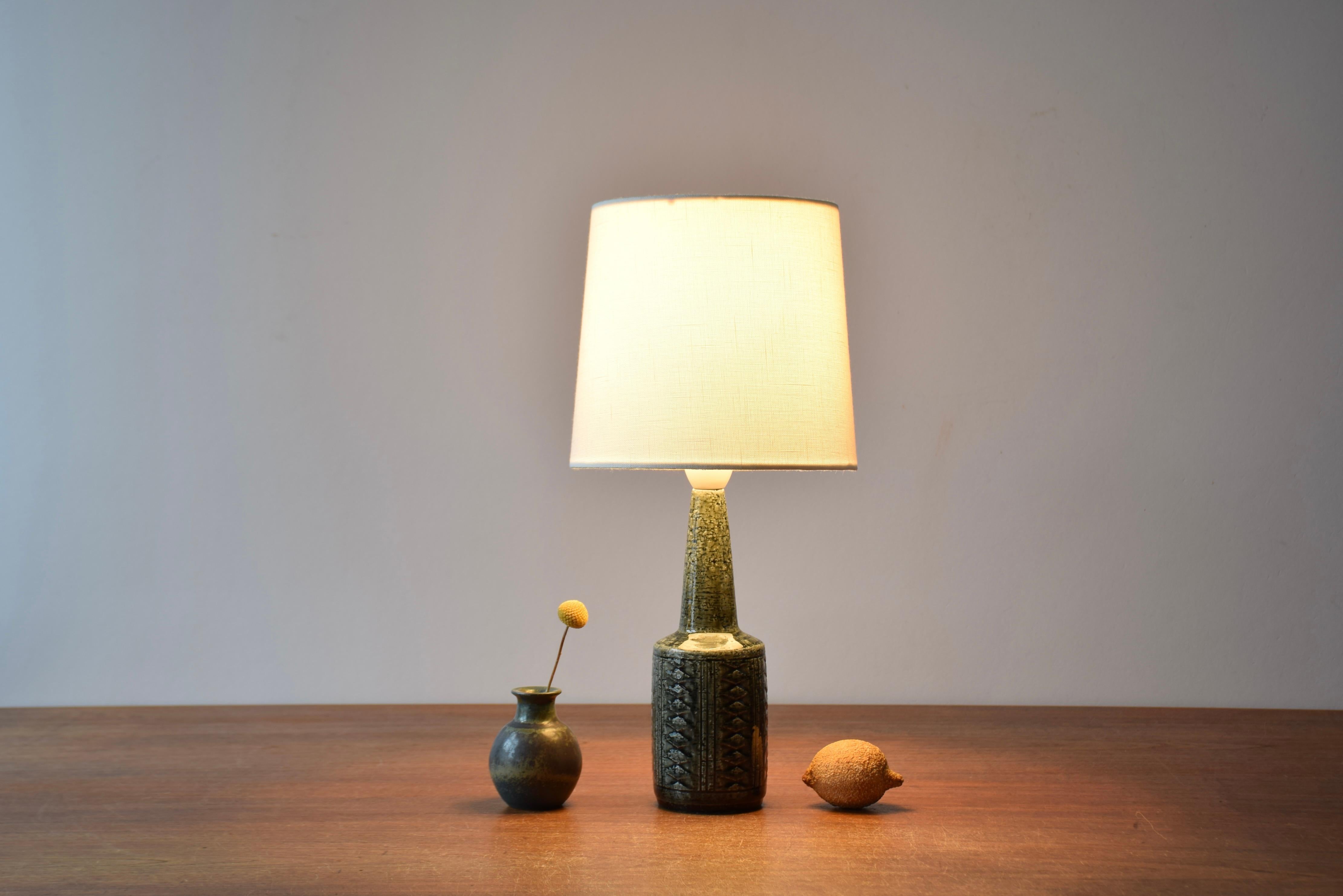 Danish Midcentury small sized table lamp or bed side lamp from Palshus ceramic workshop. 

The lamp was designed by Per Linnemann-Schmidt and made circa 1960s.
It is made with chamotte clay which gives a rough and vivid surface. The glaze is dark